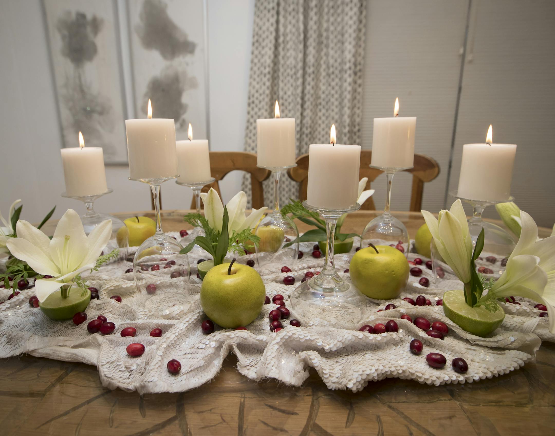Jeralyn Mohr of Full Nest's holiday centerpiece includes apples, cranberries, limes, carrot tops, flowers and candles displayed on upside-down glassware.