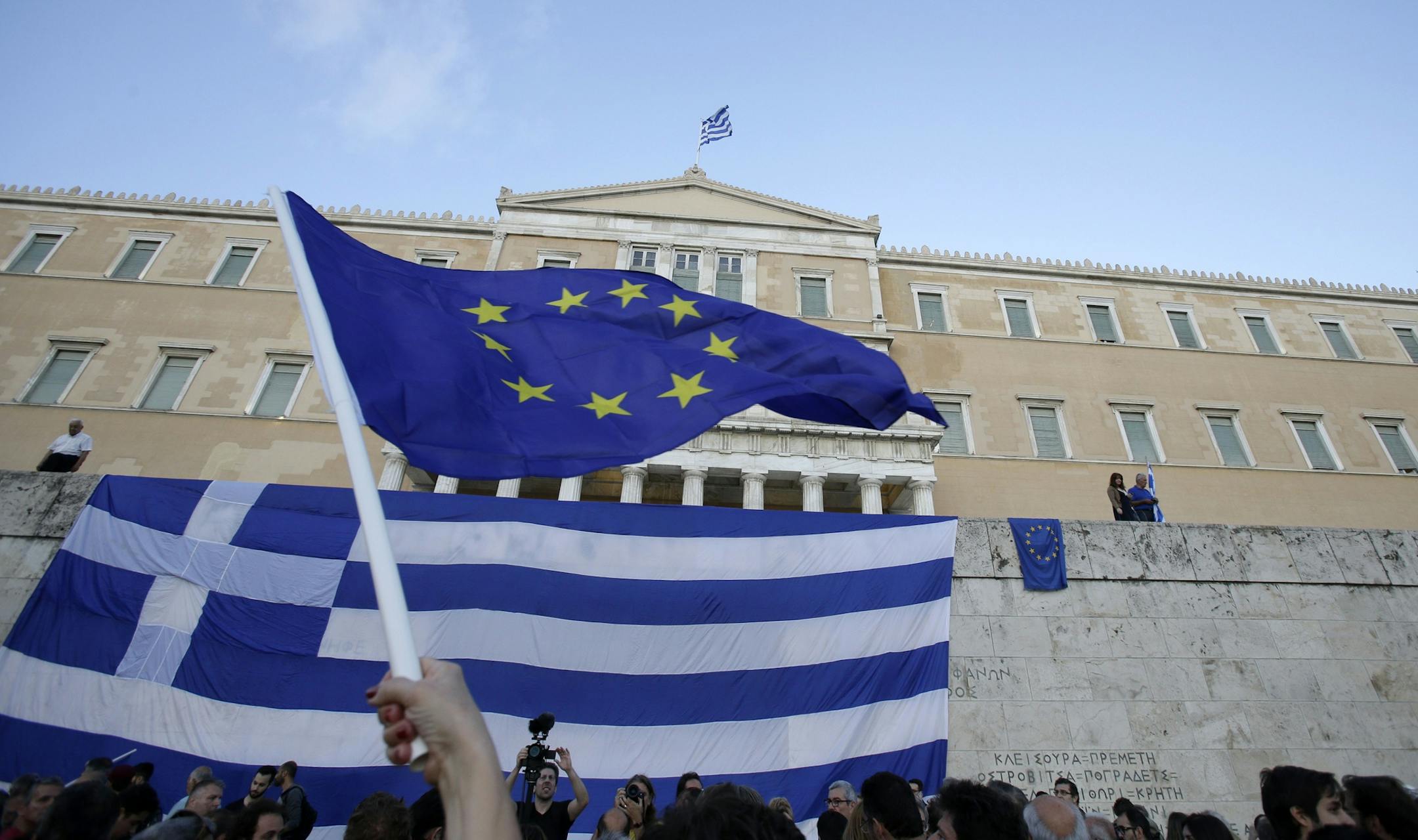 A pro-Euro demonstrator waves a European Union flag outside the Greek Parliament during a rally in Athens, Monday, June 22, 2015. Thousands of people gathered to show support for the country's future in the eurozone and the European Union. (AP Photo/Thanassis Stavrakis)