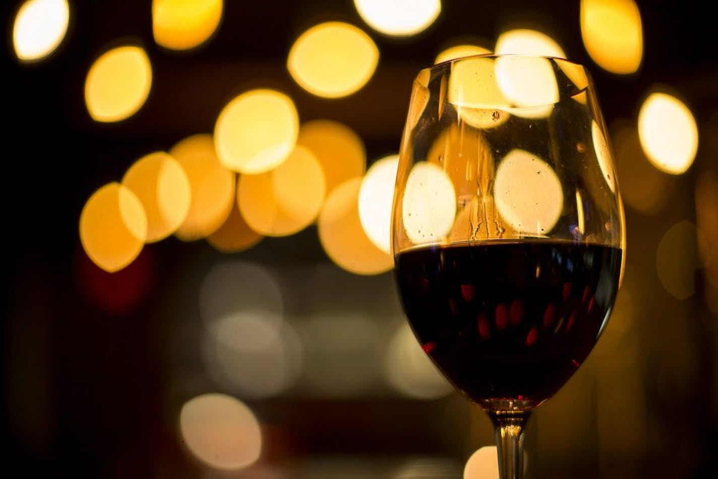 A glass of red wine sits on the bar waiting to be brought to a customer.