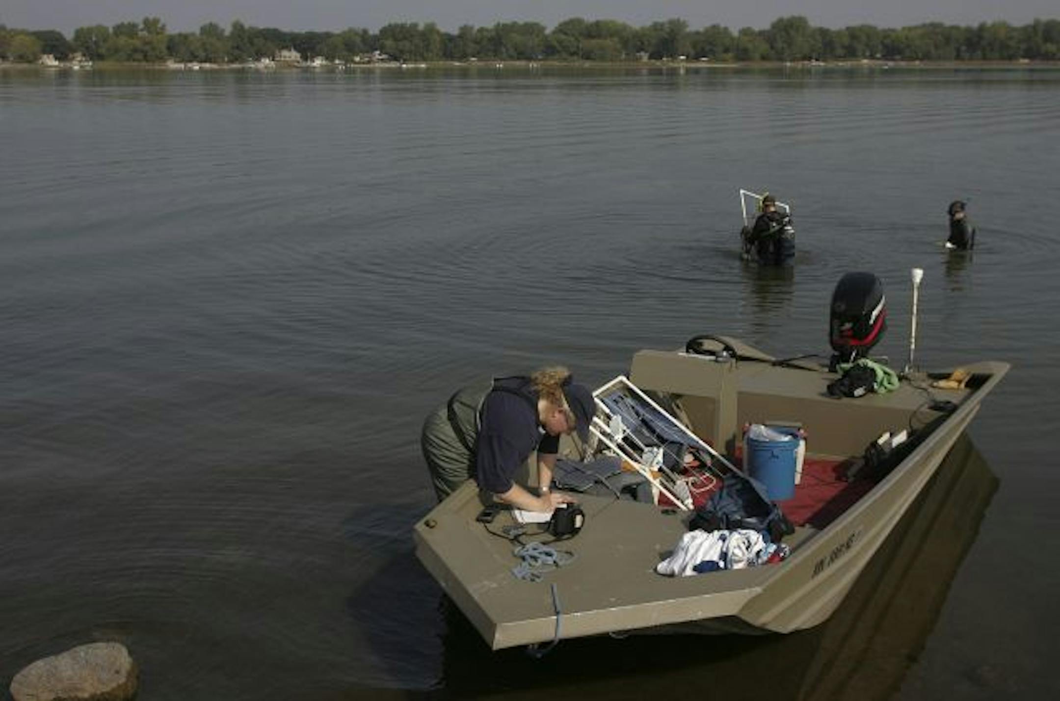 While aquatic ecologist Jo Stuckert, foreground, recorded conditions on land, aquatic scientist Steve McComas, center, and his son Connor McComas, dove to record conditions underwater, Friday, along the north shore of White Bear Lake. They three were surveying the lake to determine if conditions might support zebra mussels.