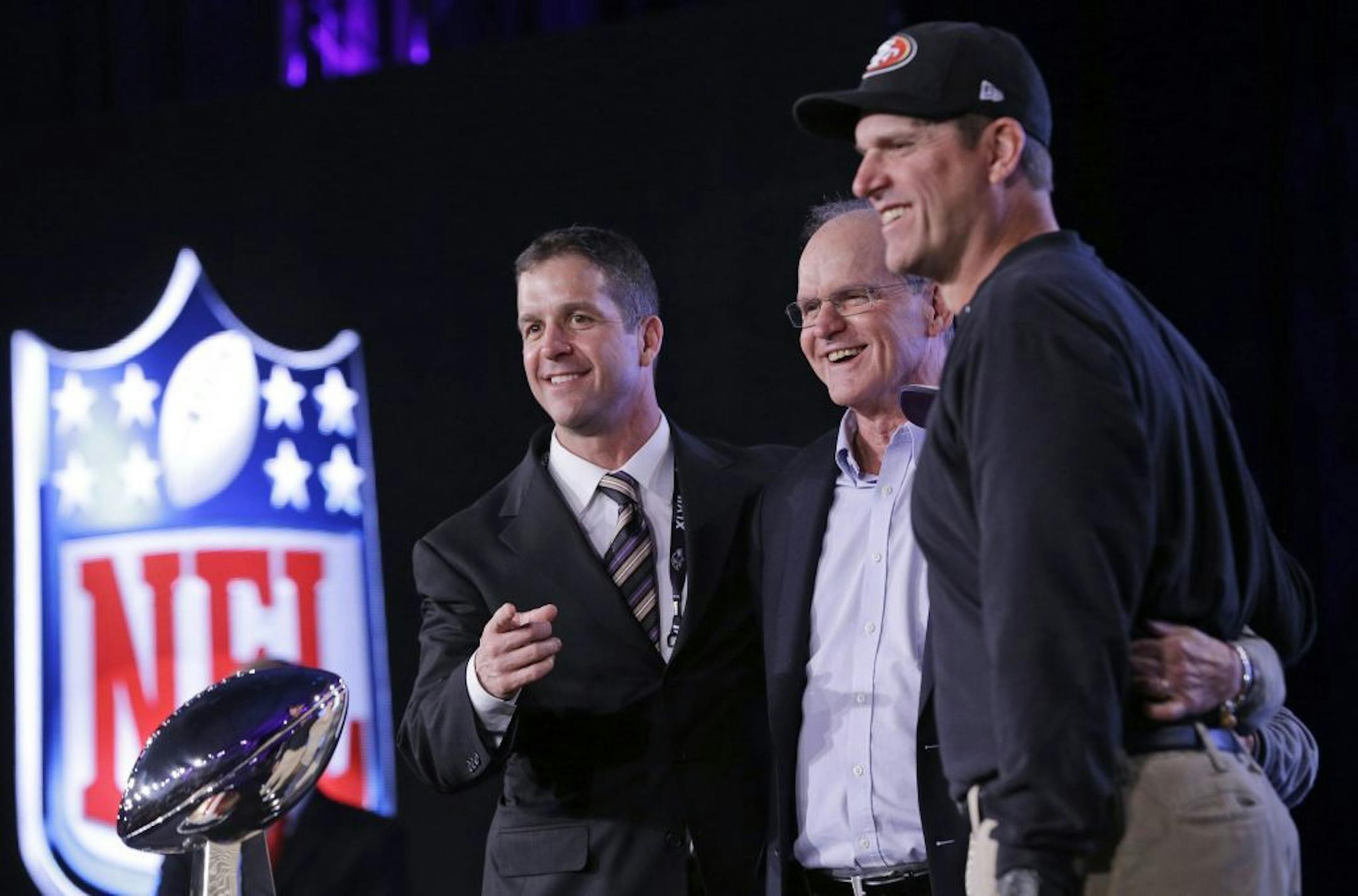 In this Feb. 1, 2013, file photo, San Francisco 49ers head coach Jim Harbaugh and Baltimore Ravens head coach John Harbaugh pose with their father Jack Harbaugh during a news conference for Super Bowl XLVII in New Orleans.