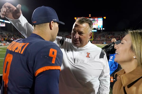 Illinois coach Bret Bielema, middle, celebrated the team’s victory against Iowa on Oct. 8 with quarterback Artur Sitkowski and Bielema’s wife, Jen