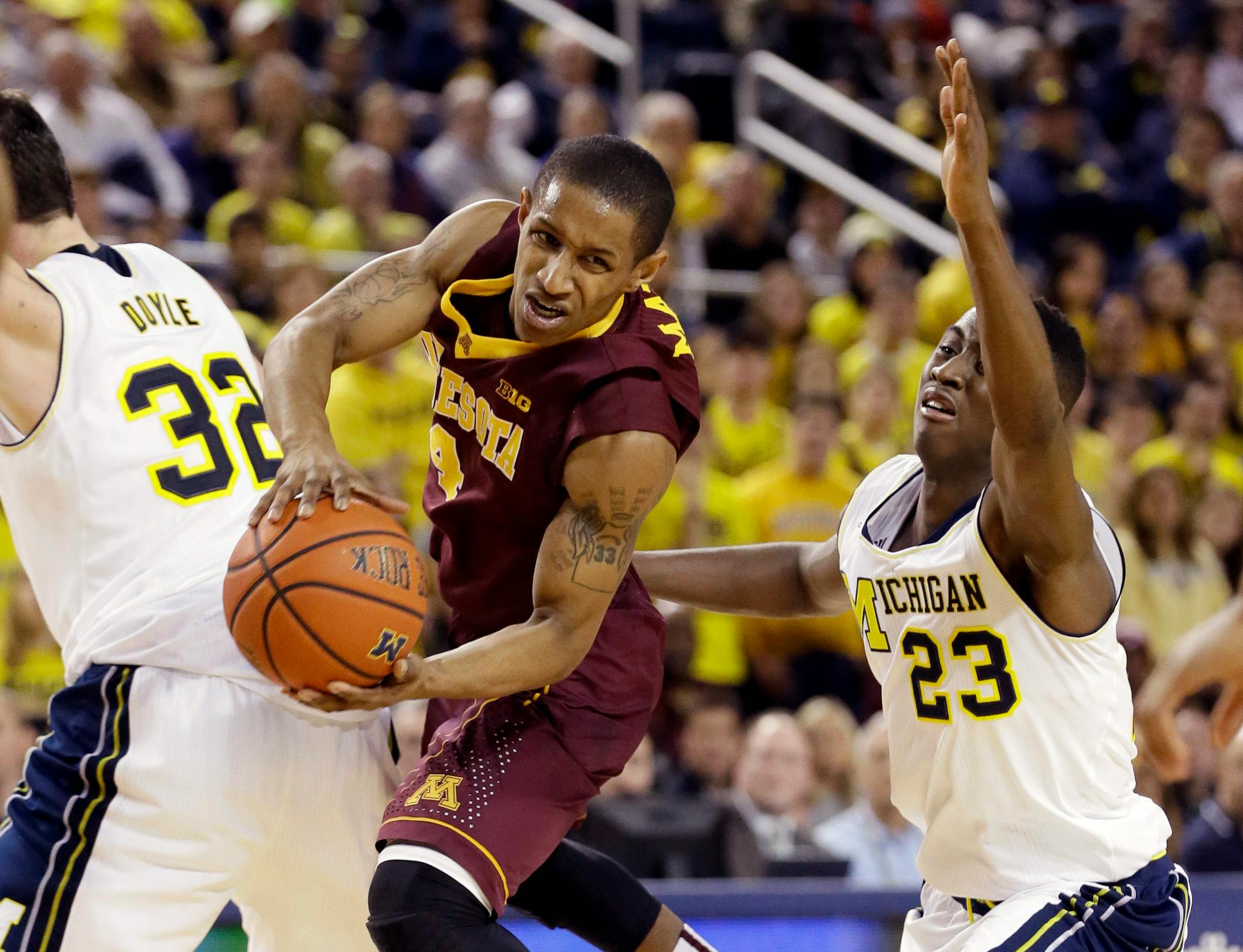 Minnesota guard DeAndre Mathieu looks to pass between Michigan forward Ricky Doyle (32) and guard Caris LeVert (23) during the first half of an NCAA basketball game, Saturday, Jan. 10, 2015, in Ann Arbor, Mich. (AP Photo/Carlos Osorio)