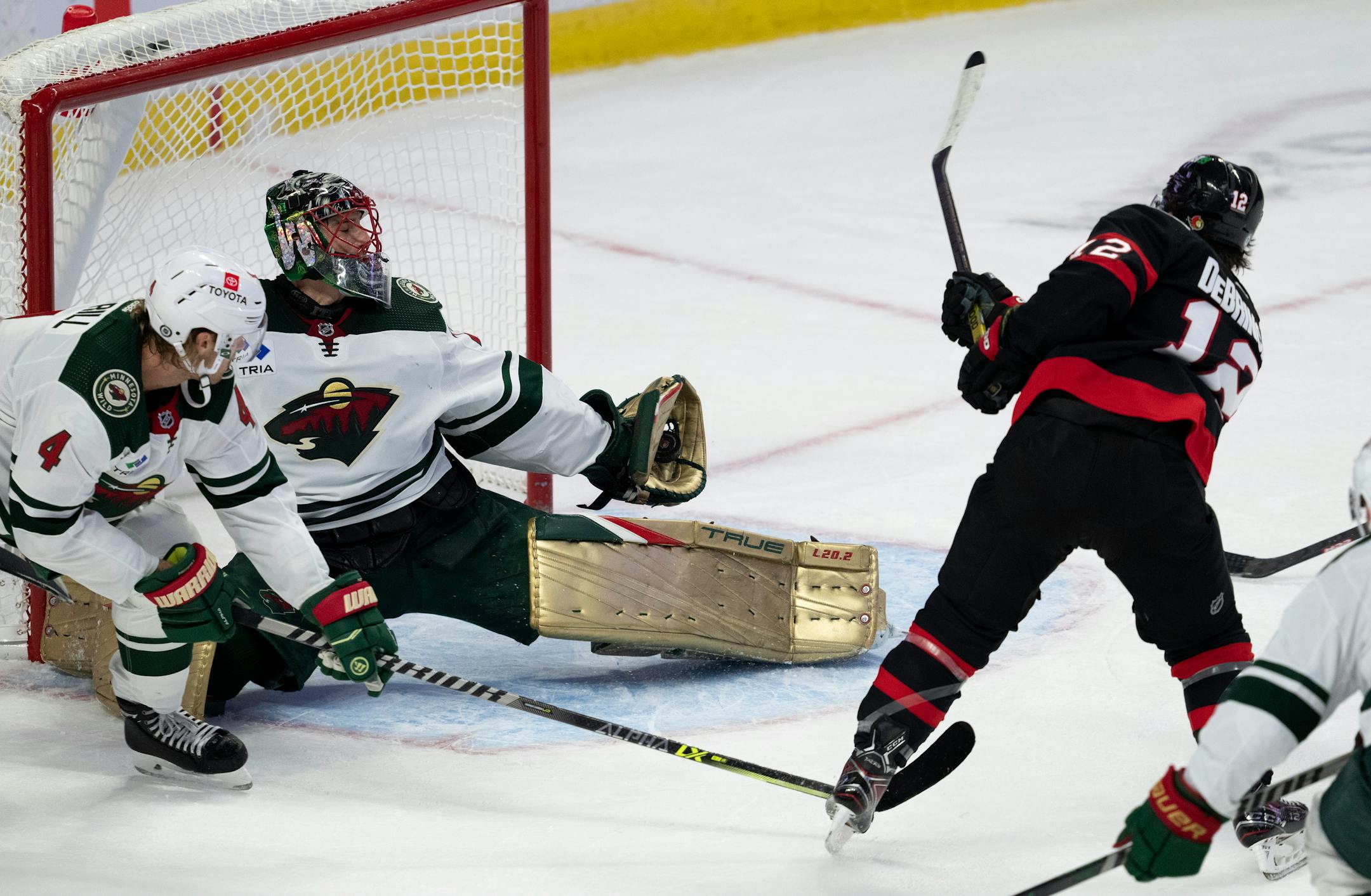 Minnesota Wild defenseman Jon Merrill looks on as goaltender Marc-Andre Fleury reaches back to make a glove save on Ottawa Senators right wing Alex DeBrincat during the first period of an NHL hockey game, Thursday, Oct. 27, 2022 in Ottawa, Ontario. (Adrian Wyld/The Canadian Press via AP)