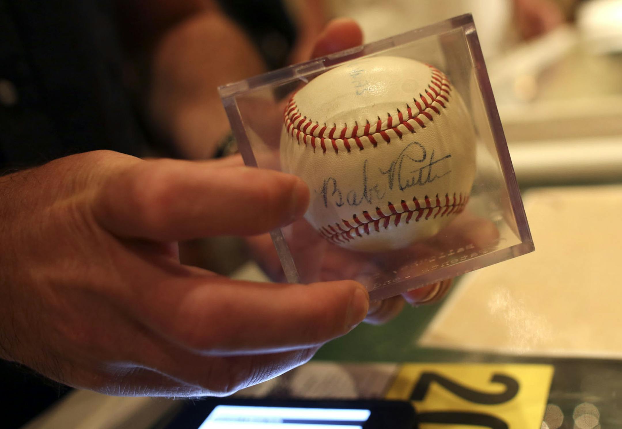 Peter Ullman, of St Paul, held a autographed Babe Ruth ball during a preview at the Sheraton West in Minnetonka Min., Wednesday, July 24, 2013. The Department of Commerce is holding an auction of an estimated 5,000 abandoned safe-deposit box contents Thursday and Friday run by Schultz Auctioneers. ] (KYNDELL HARKNESS/STAR TRIBUNE) kyndell.harkness@startribune.com