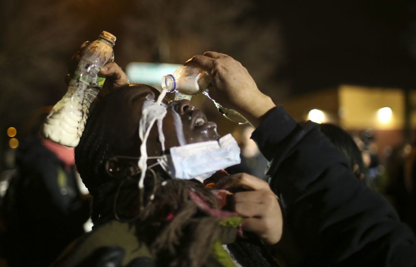 Friends helped a demonstrator by giving her a milk eye wash after police used pepper spary to disperse demonstrators from a side entrance to the 4th Precinct headquarters Wednesday night in Minneapolis.