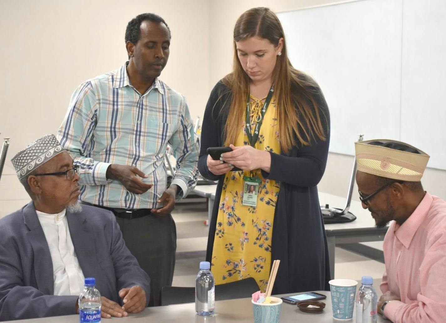 UCare provided a $25,000 grant for the Faribault Families First Alliance family engagement program to teach Somali parents how to download an app to track their children's grades, attendance and school activites. In photo, &#x201c;helpers&#x201d; Faribault High School Assistant Principal Shawn Peck, and Adult Education and Enrichment Coordinator Cassie Ohnstad demonstrate the app to two Somali fathers.