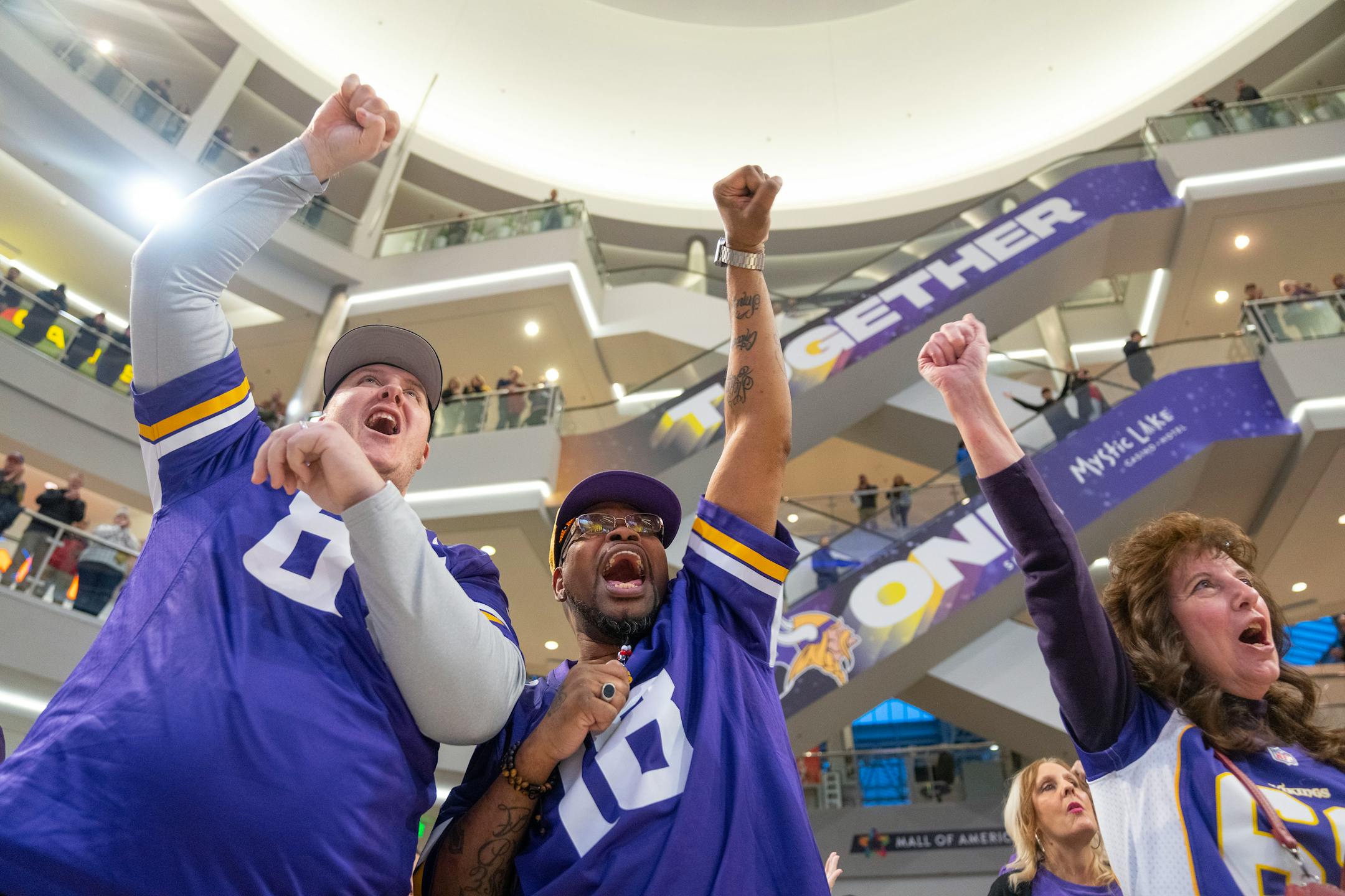Rob Bernurn, Edward Milton and Mary Johnson, left to right, cheer as a Vikings fan rally kicks off Friday, Jan. 13, 2023 at the Mall of America in Bloomington, Minn.