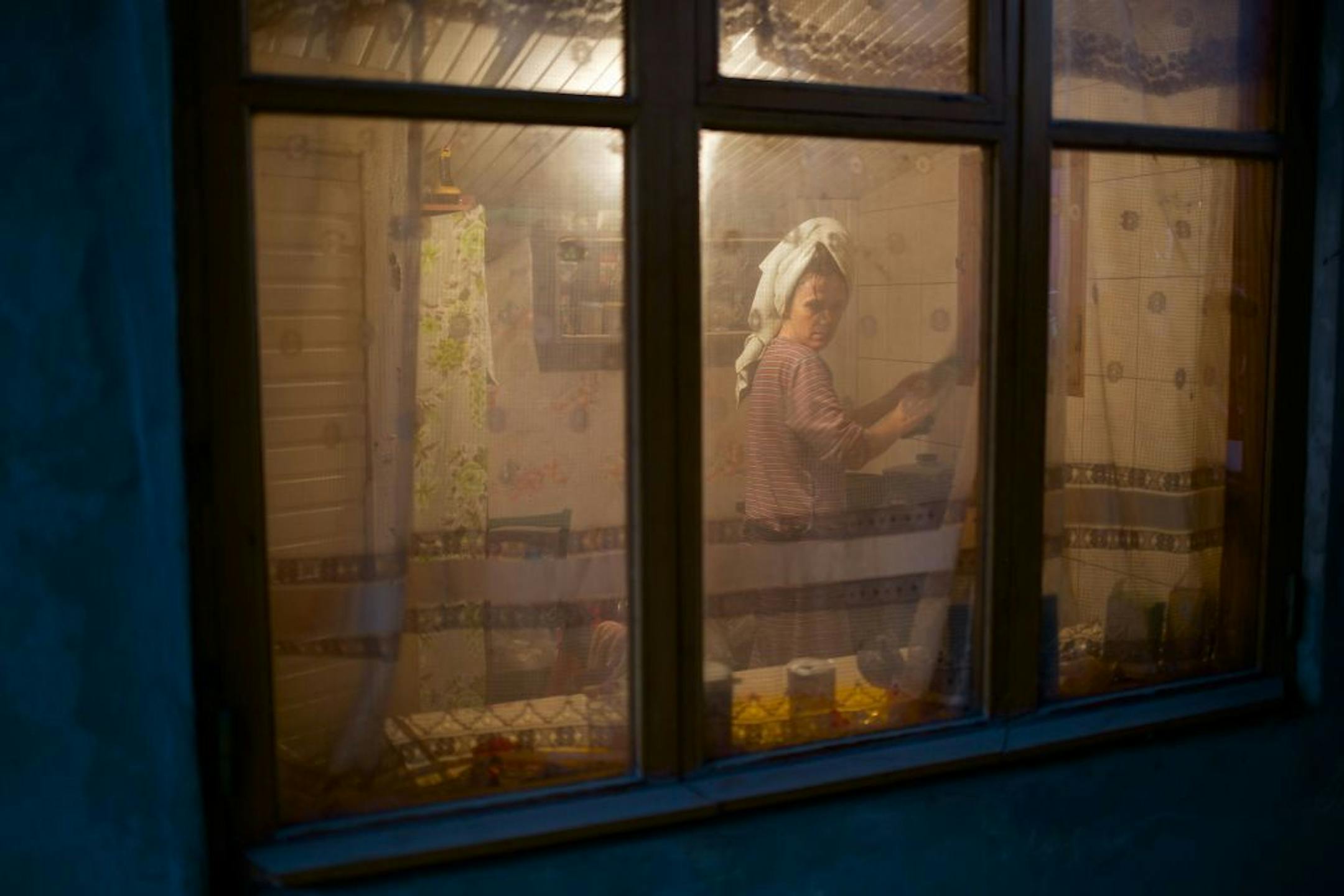 In this photo taken on Wednesday, Nov. 27, 2013, a woman washes up dishes in her kitchen in the village of Vesyoloye, outside Sochi, Russia.