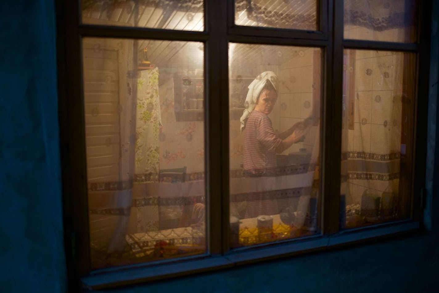 In this photo taken on Wednesday, Nov. 27, 2013, a woman washes up dishes in her kitchen in the village of Vesyoloye, outside Sochi, Russia.