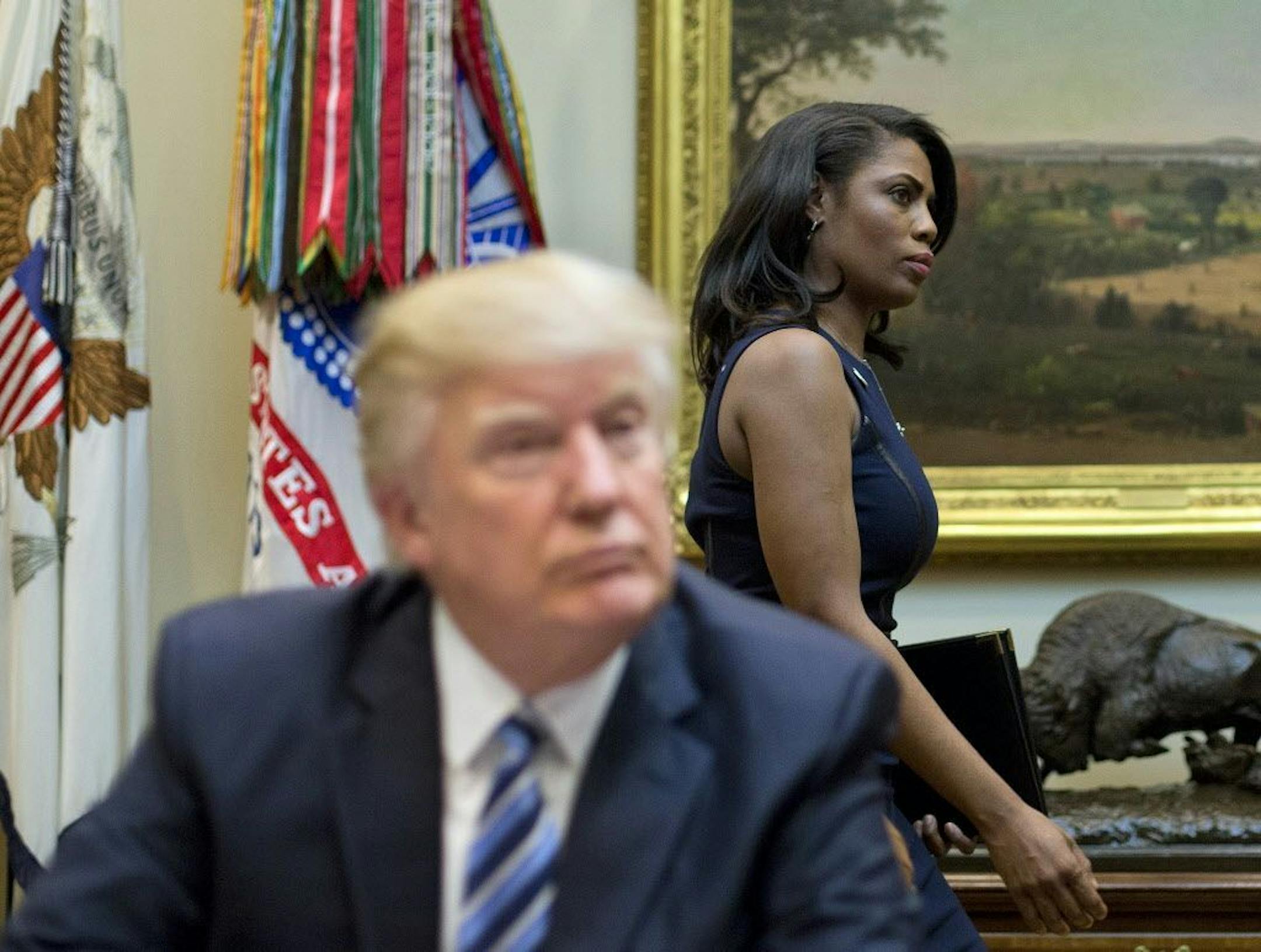 FILE - In this March 12, 2017 file photo, White House Director of communications for the Office of Public Liaison Omarosa Manigault, right, walks past President Donald Trump during a meeting on healthcare in the Roosevelt Room of the White House.