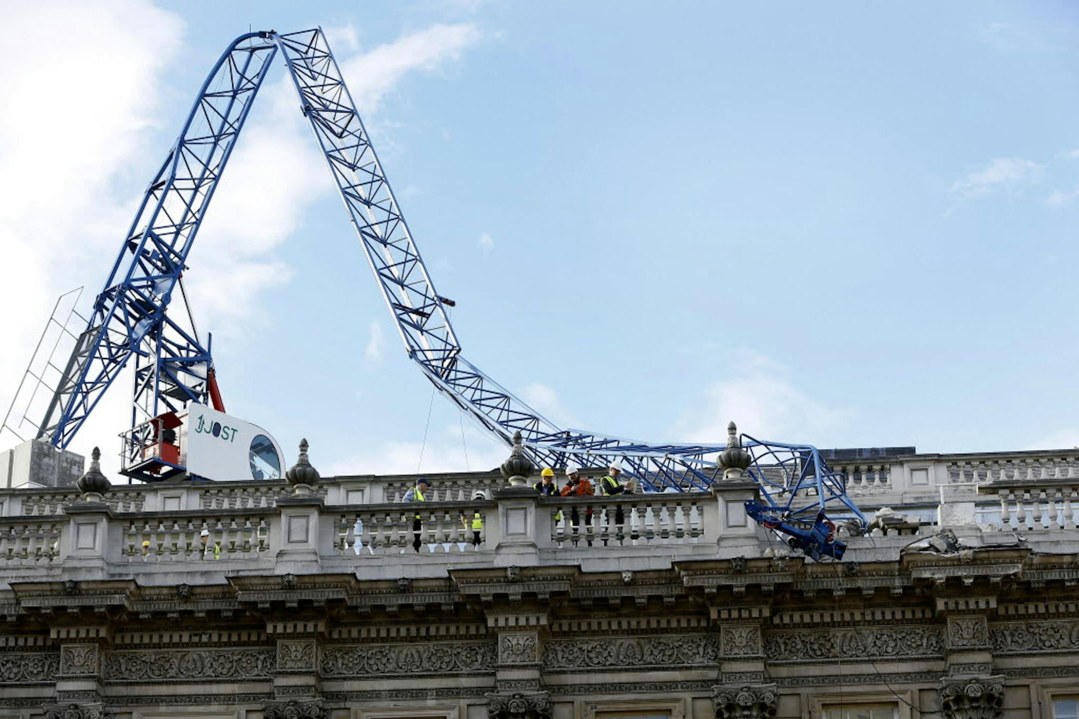 Workmen survey the damage caused by a crane brought down by high winds onto the roof of the Cabinet Office in Whitehall, near Downing Street in London, Monday.