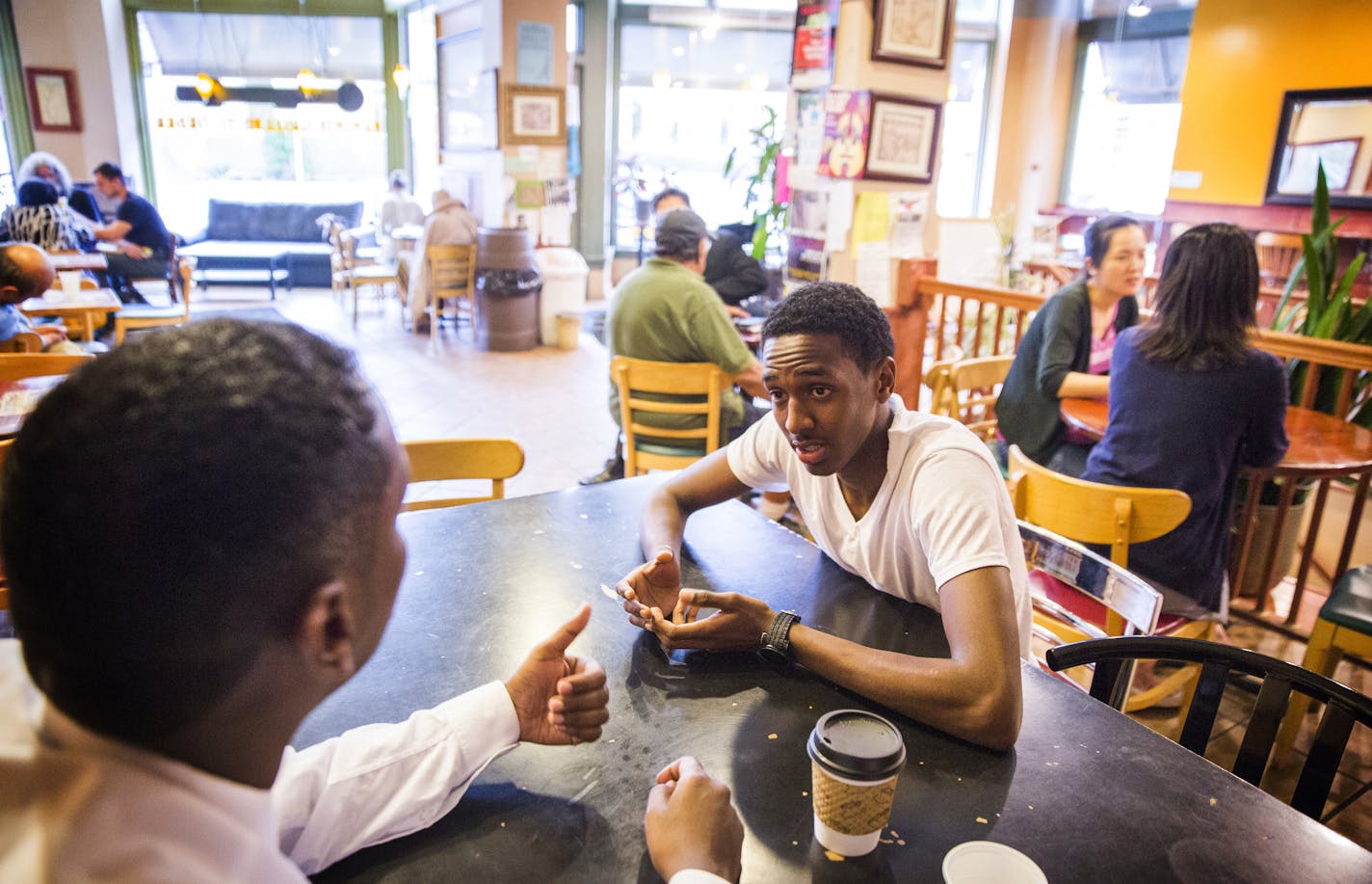 Minneapolis City Councilman Abdi Warsame, left, talks with Mubashir Jeilani, 19, at Mapps Coffee Riverside in Minneapolis on Friday, May 29, 2015. ] LEILA NAVIDI leila.navidi@startribune.com /