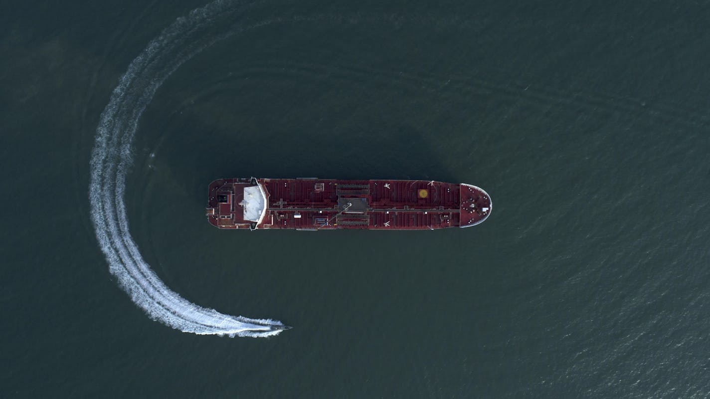 In this Sunday, July 21, 2019 photo, an aerial view shows a speedboat of Iran's Revolutionary Guard moving around the British-flagged oil tanker Stena Impero which was seized in the Strait of Hormuz on Friday by the Guard, in the Iranian port of Bandar Abbas. Global stock markets were subdued Monday while the price of oil climbed as tensions in the Persian Gulf escalated after Iran's seizure of a British oil tanker on Friday. (Morteza Akhoondi/Tasnim News Agency via AP)