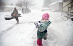 Jared Hanson playfully sprays his daughter, Kaityln, 7, with a shovel full of snow as she builds a snow fort while her clears the sidewalk in front of
