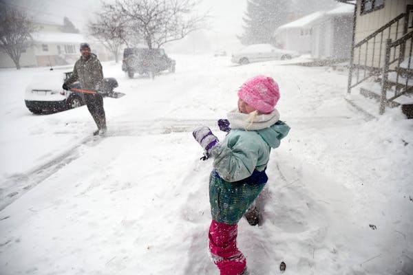 Jared Hanson playfully sprays his daughter, Kaityln, 7, with a shovel full of snow as she builds a snow fort while her clears the sidewalk in front of