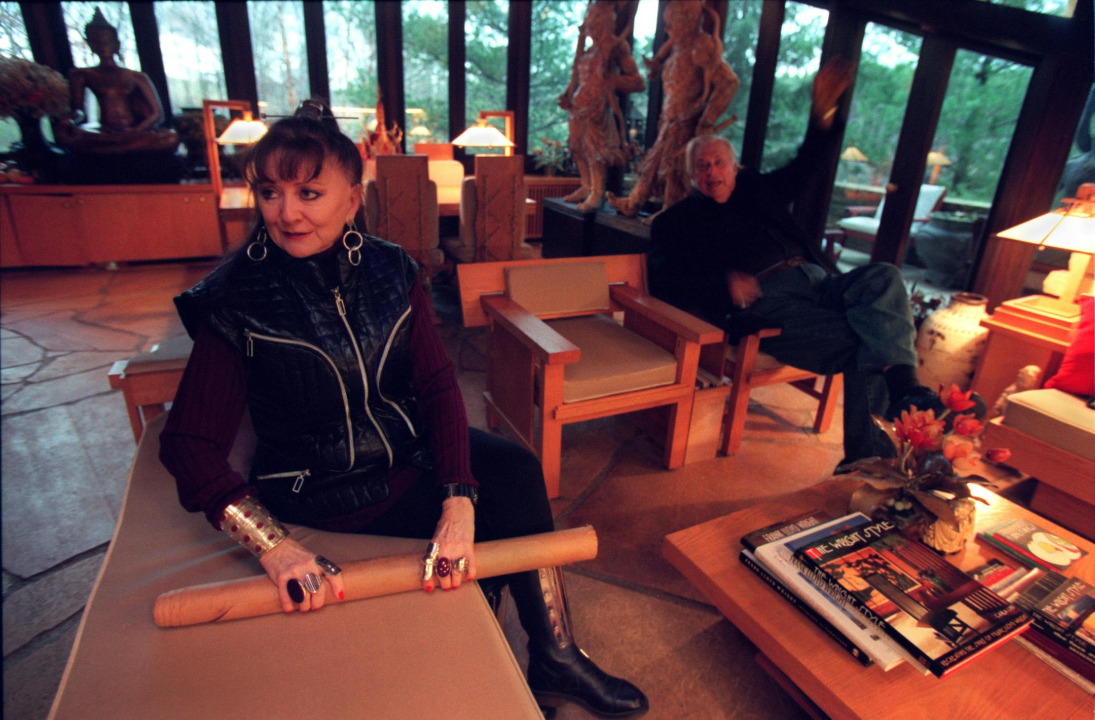 Virginia and Don Lovness, who built and live in two houses Frank Lloyd Wright designed. -- (Left to right) Virginia Lovness rolls up plans for more cottages she and her husband, Don (at right, in back) hope to build. Note--Please check caption info with Linda Mack.) They are seated in the livingroom of the cottage.