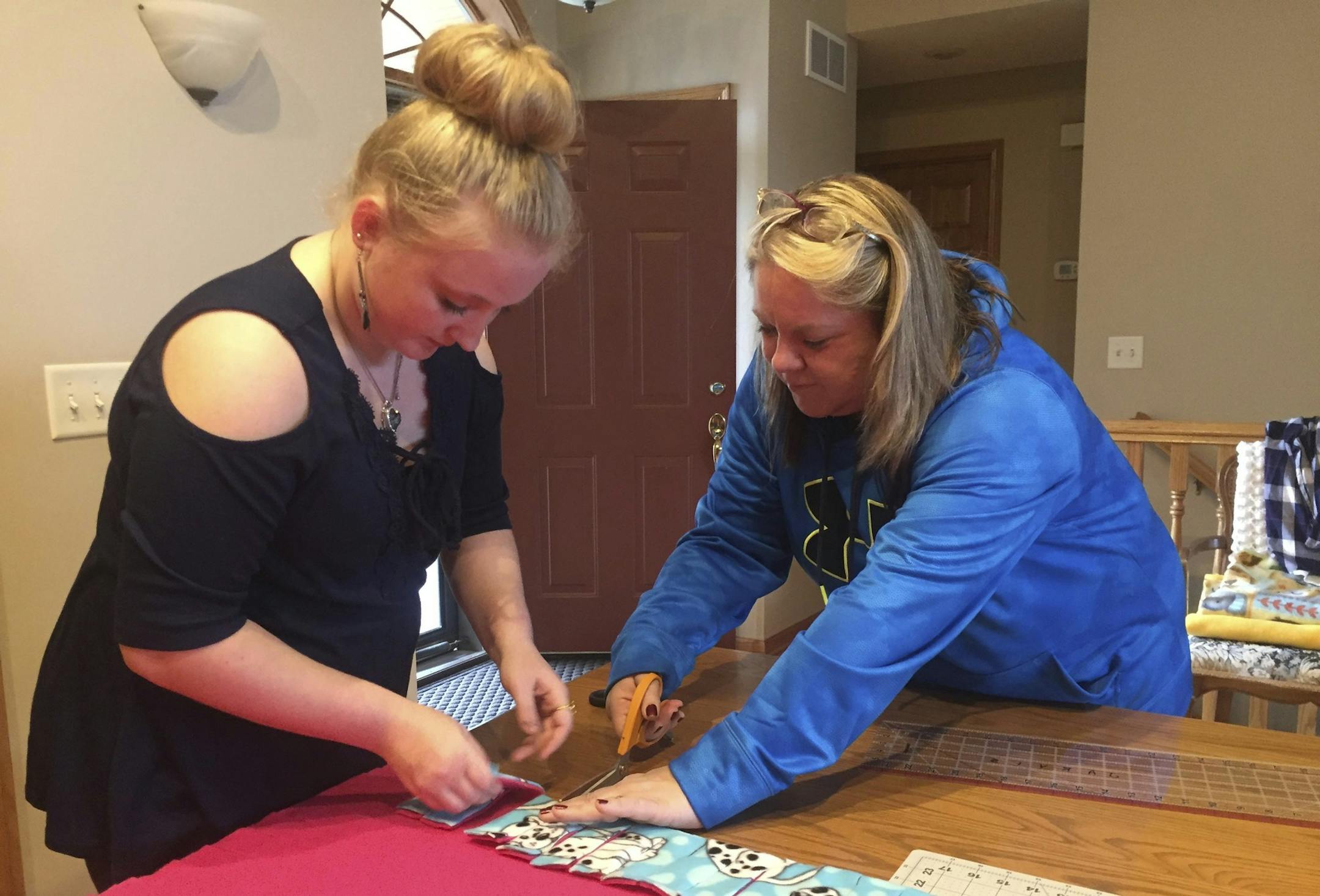ADVANCE FOR WEEKEND EDITIONS, DEC. 10-11 - In this Dec. 4, 2016 photo, Hailey Sherwood, 16, left, gets help making a blanket from her adoptive mother, April, in Nicollet, Minn. When Hailey was first brought to April to be fostered as an infant, she was given a blanket. She's kept the blanket ever since, and recently came up with a project to make blankets for children in new foster homes. (Brian Arola /The Free Press via AP) ORG XMIT: MNMAN101