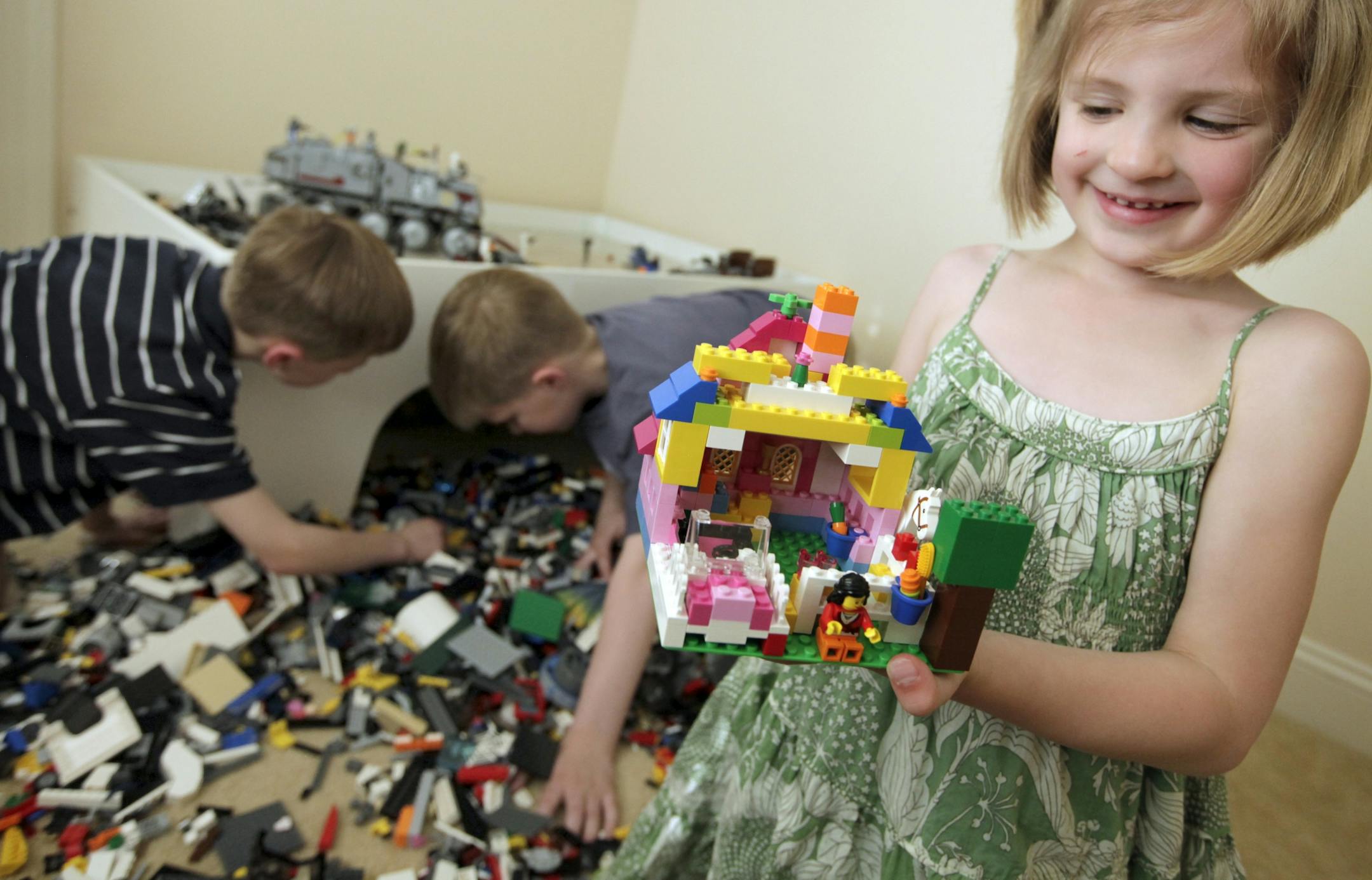 Ella, 5, holds a Lego house that her brother Henry helped build. Their family has up to 20,000 of the colorful play blocks.