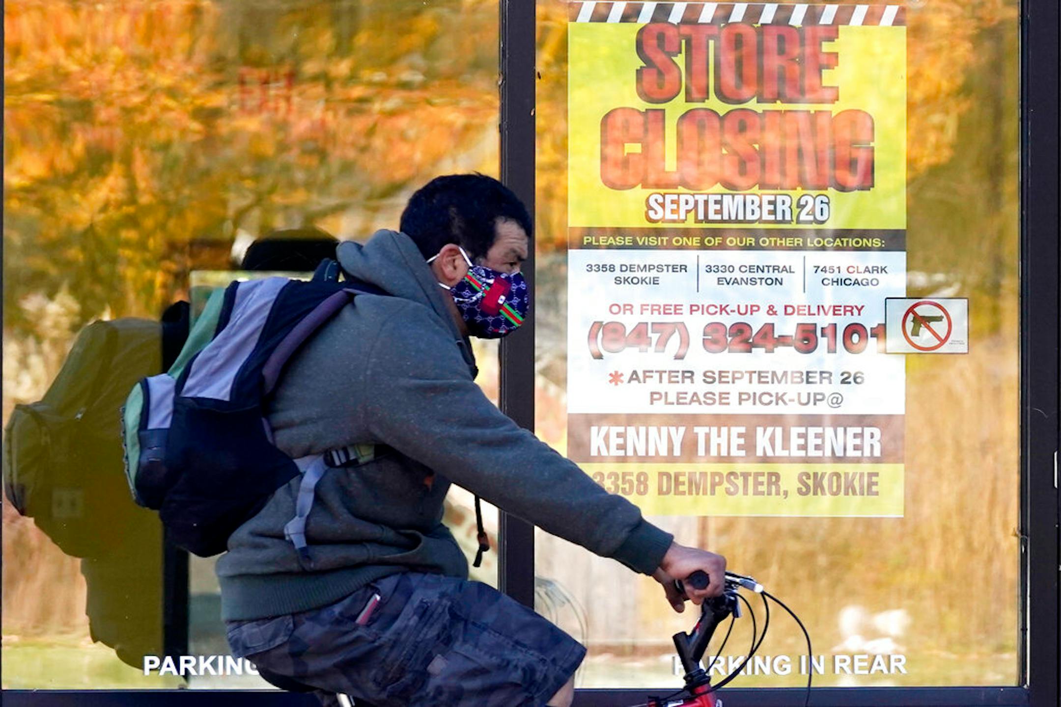 A man wearing a face mask rode a bicycle Nov. 6 past a closed store in Wilmette, Ill.