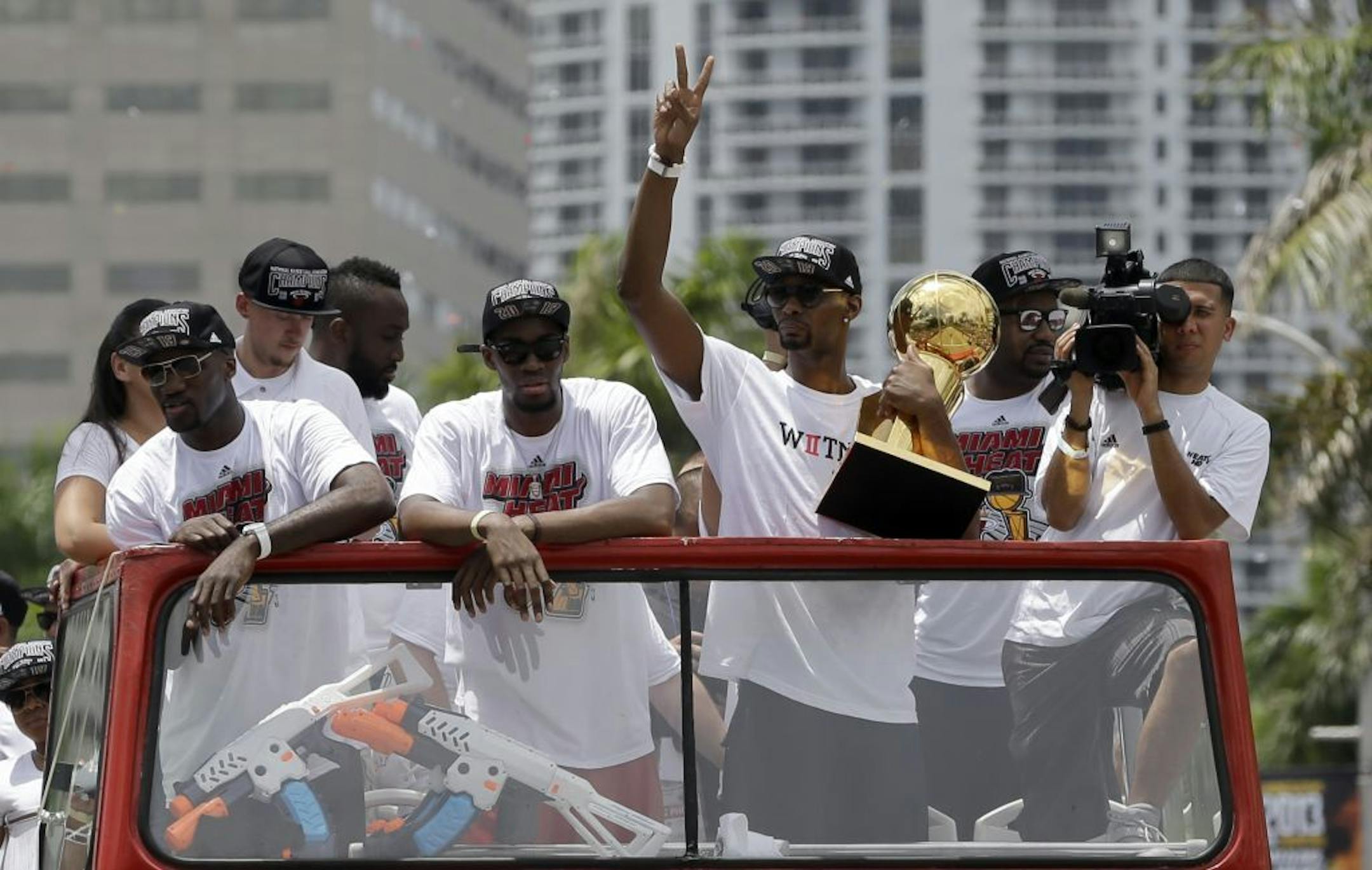 NBA Champion Miami Heat's Chris Bosh, right, holds the NBA championship trophy during a parade honoring the team in Miami, Monday, June 24, 2013.
