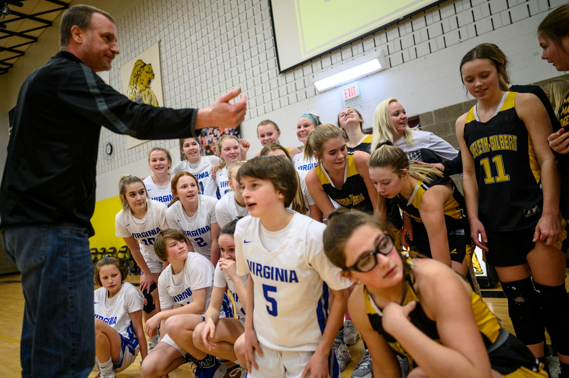 Eveleth-Gilbert Athletic Director Chad Hazelton, left, coordinates a group photo of the Virginia and Eveleth-Gilbert girls basketball teams after their last-ever game against each other Monday, Feb. 21, 2022. The two teams will consolidate into the New Rock Ridge district.