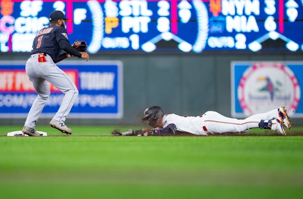 Minnesota Twins first baseman Jose Miranda (64) slides into second base while Cleveland Guardians shortstop Amed Rosario (1) attempts to make a play i