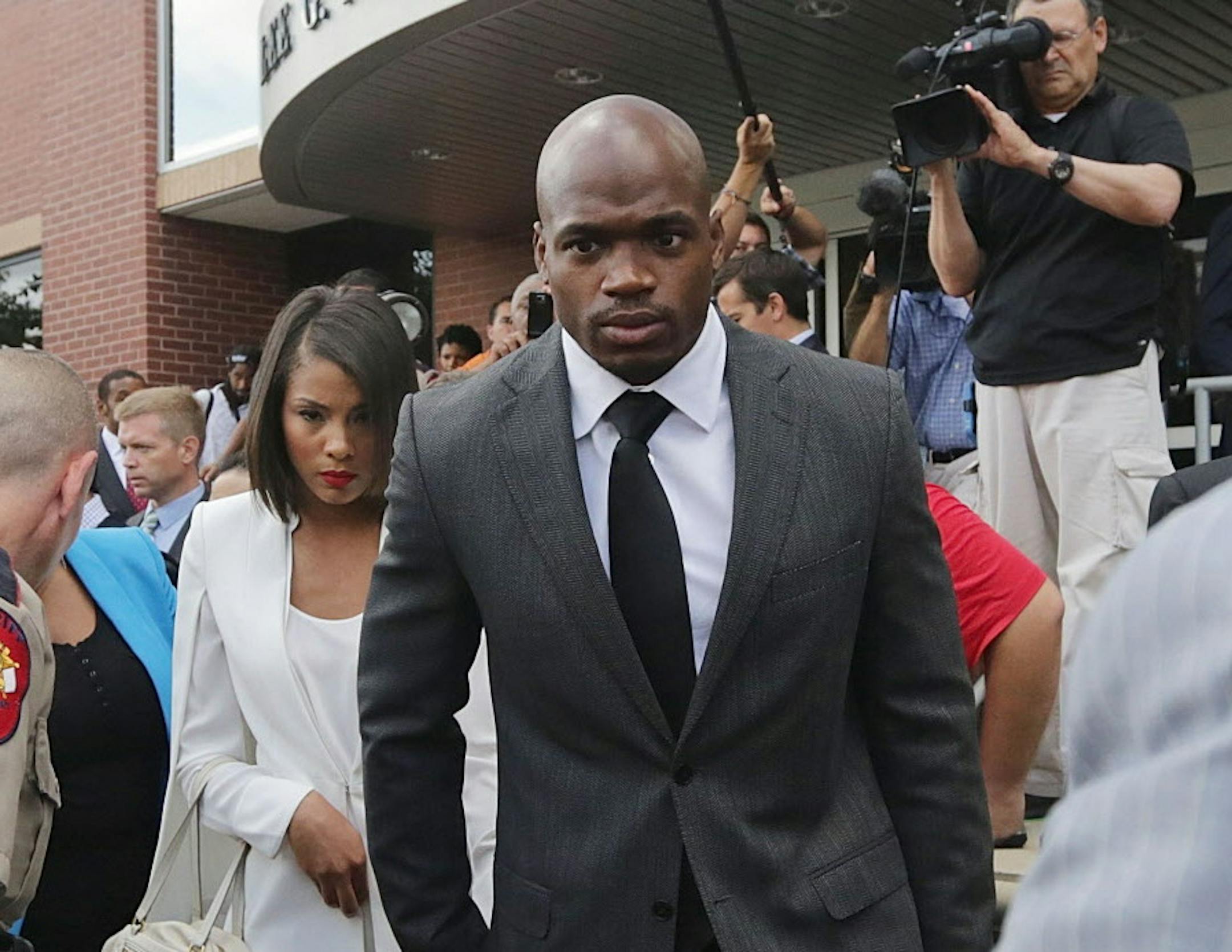 Minnesota Vikings running back Adrian Peterson leaves court accompanied by his wife, Ashley Brown Peterson, in Conroe, Texas, Wednesday, Oct. 8, 2014. A judge tentatively set a Dec. 1 trial date for Peterson on a charge of felony child abuse for using a wooden switch to discipline his 4-year-old son earlier this year. (AP Photo/Houston Chronicle, Billy Smith II)