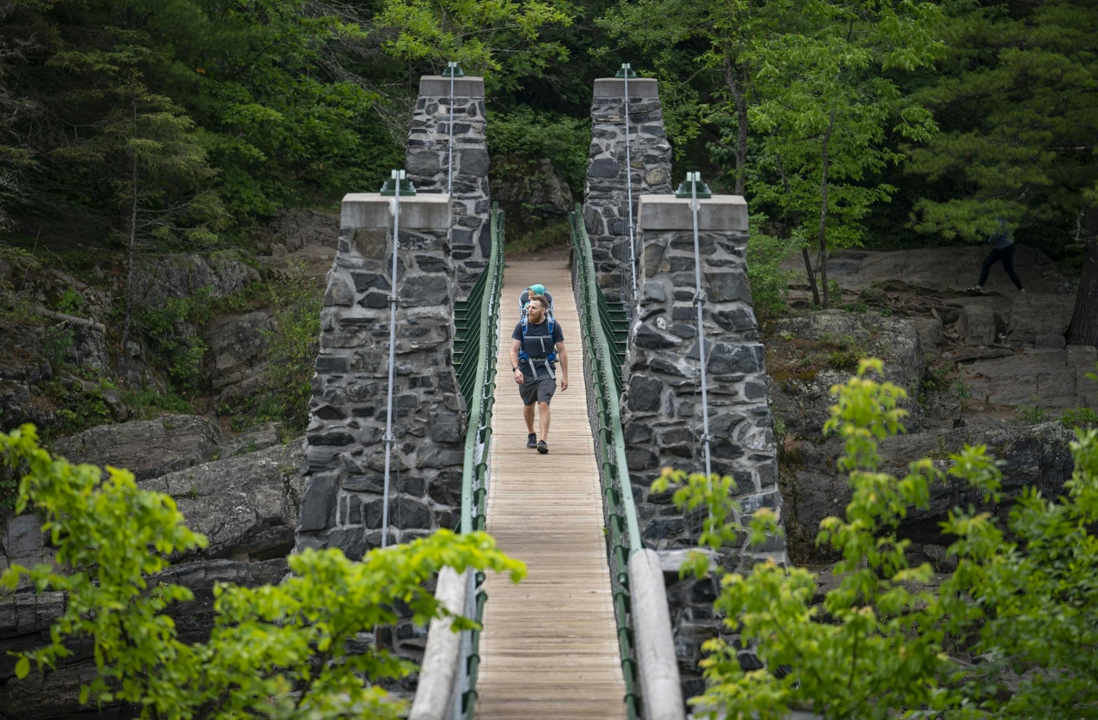 A man carried his child on his back while crossing the swinging bridge at Jay Cooke State Park on Wednesday.