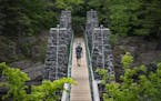 A man carried his child on his back while crossing the swinging bridge at Jay Cooke State Park on Wednesday.