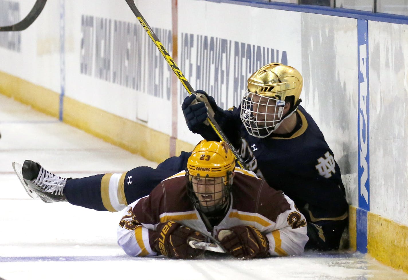 Minnesota's Ryan Norman (23) and Notre Dame's Ben Ostlie (8) crash into the boards during the second period of an NCAA regional men's college hockey tournament game, Saturday, March 25, 2017 in Manchester, N.H. (AP Photo/Mary Schwalm)