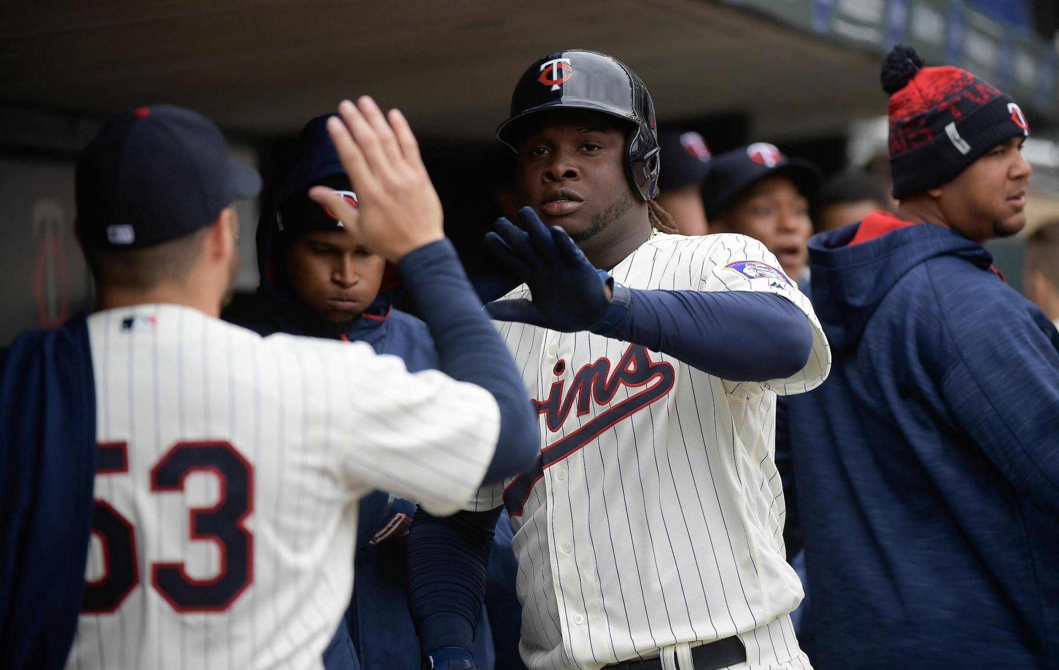 Minnesota Twins third baseman Miguel Sano (22) high fived teammates, including starting pitcher Hector Santiago (53), after scoring a run off an RBI double by Eduardo Escobar in the bottom of the second innning.