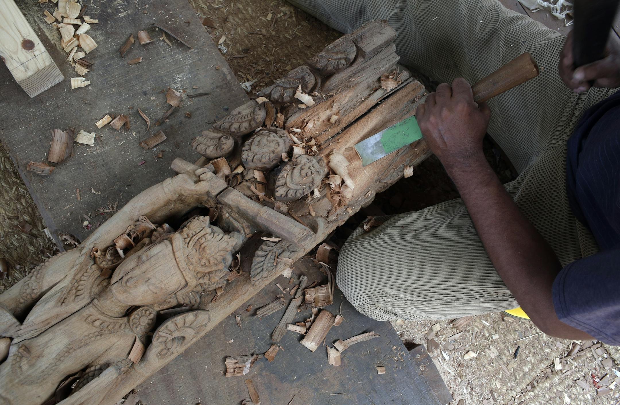In this photo taken Wednesday, July 19, 2017, a woodworker from the Newar ethnic community carves wood in Lalitput, Nepal. In the rubble of Nepal's 2015 earthquake, a team of dedicated woodworkers is finding inspiration to recreate what was lost. Centuries-old Char Narayan and Hari Shankara temples were completely destroyed by the massive April 2015 earthquake that shook the Himalayan nation, killing nearly 9,000 people. The temples were the jewel of the Patar Durbar Square, which is thronged by