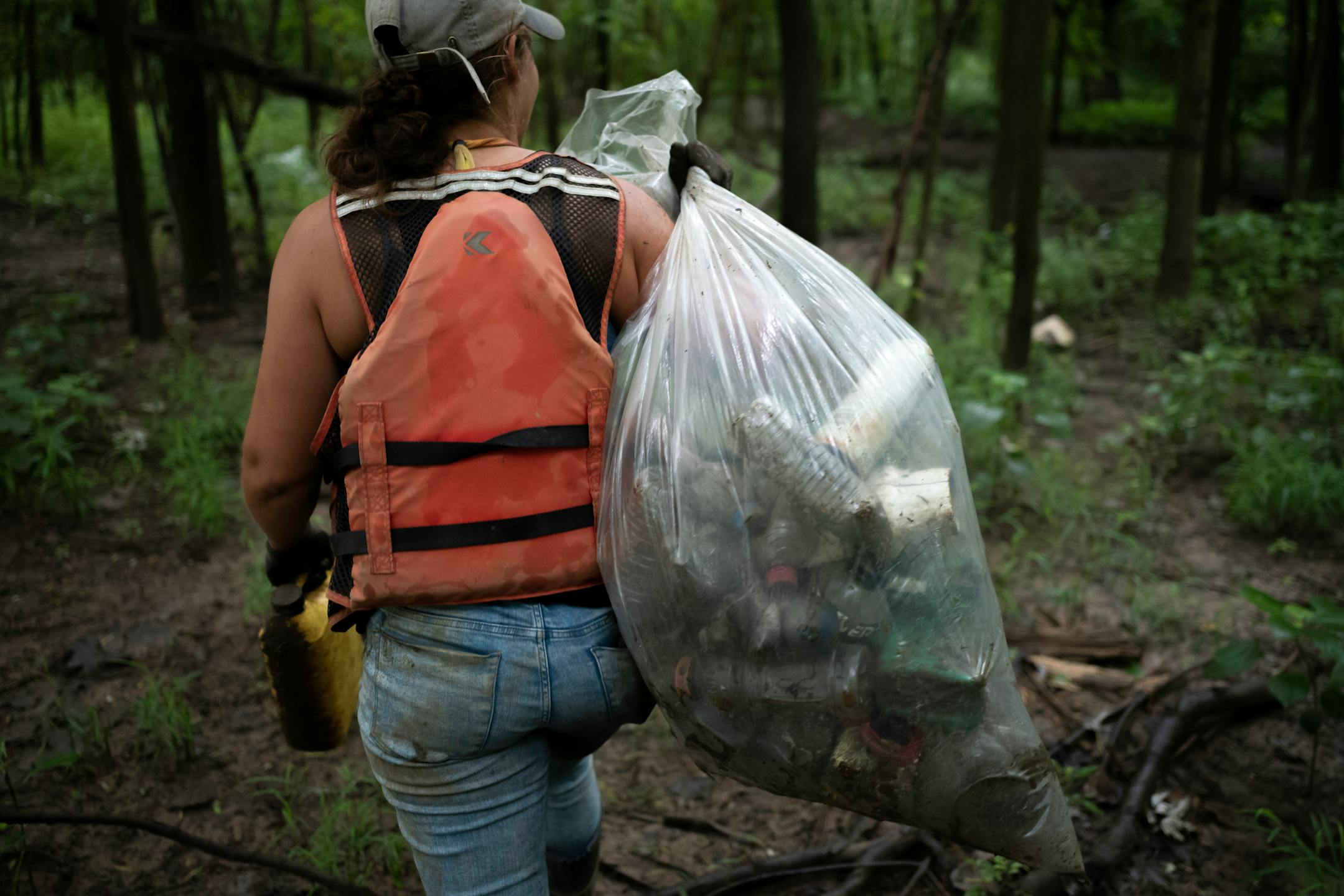 Callie Schafer hauls back a bag full of single-use plastics she gathered while working near the Ohio River on Tuesday, July 13, 2021 in Cincinnati, Ohio.