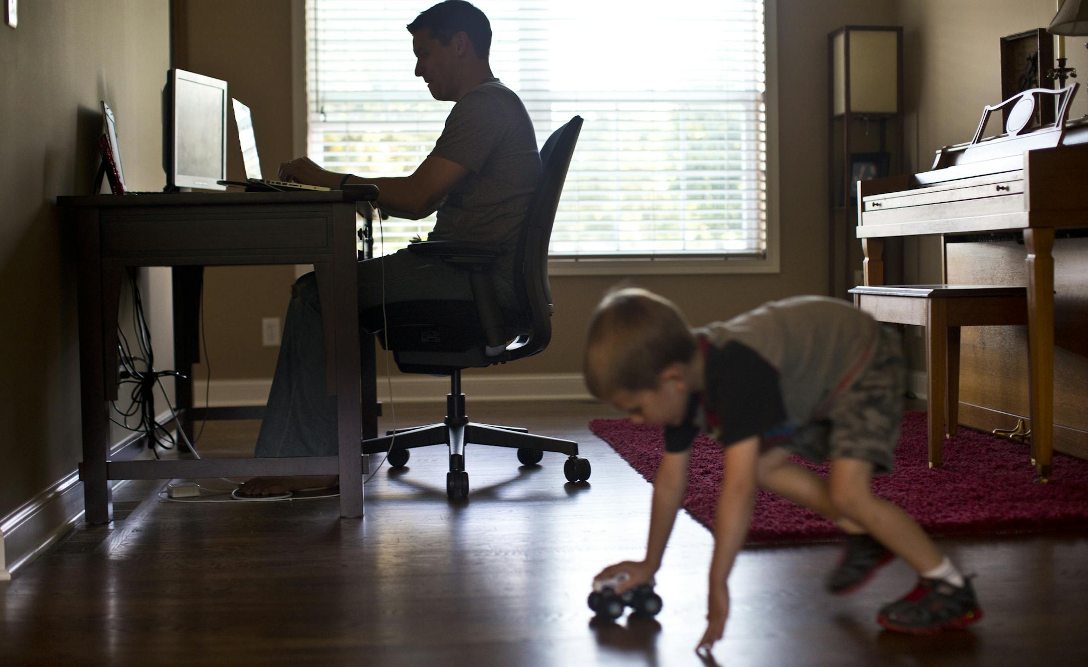Adam Weller worked on a paper while his son John, 5, played with his cars at home in Savage, Minn., on Tuesday, September 25, 2013. Weller is one of the first students at Capella University to take one of its new brand of FlexPath courses. He says the self-paced courses work well with his busy schedule, but "I could definitely see drawbacks for folks who are not extremely self-motivated and disciplined." ] (RENEE JONES SCHNEIDER ‚Ä¢ reneejones@startribune.com)