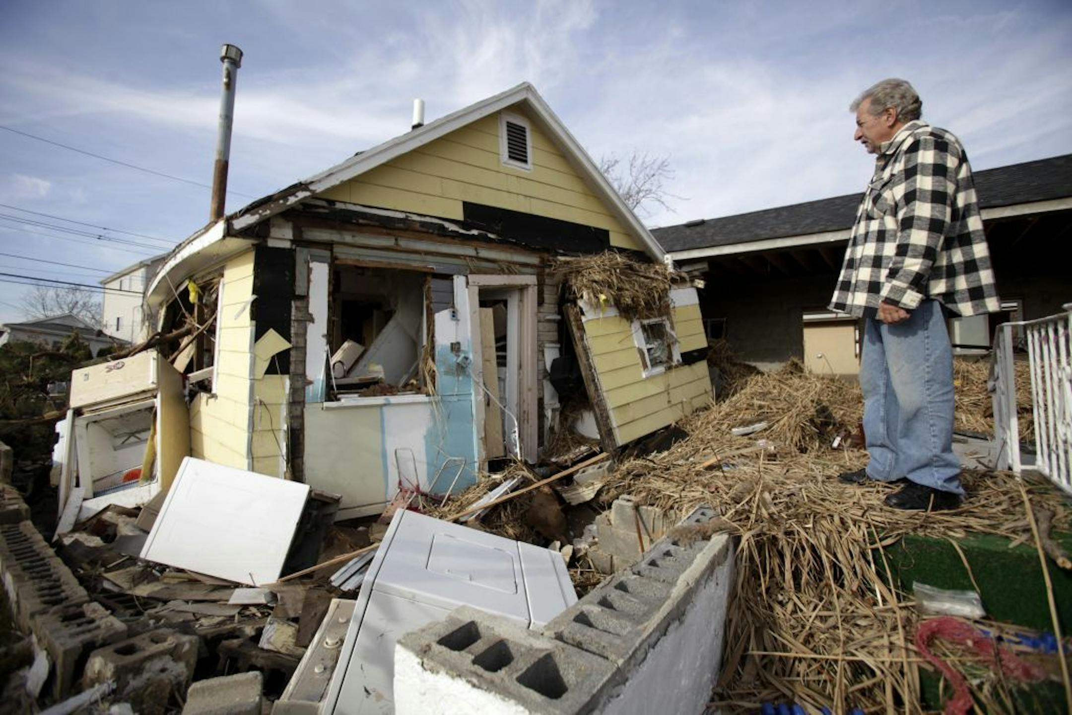 FILE - In this Nov. 20, 2012 file photo, Joe Vanvaketis looks at his Superstorm Sandy damaged home in the Oakwood Beach section of Staten Island, New York. The neighborhood, where three people died during Sandy, will be the first to get state-sponsored home buyouts, according to Gov. Andrew Cuomo outlined the planned program during a visit to the borough on Monday.
