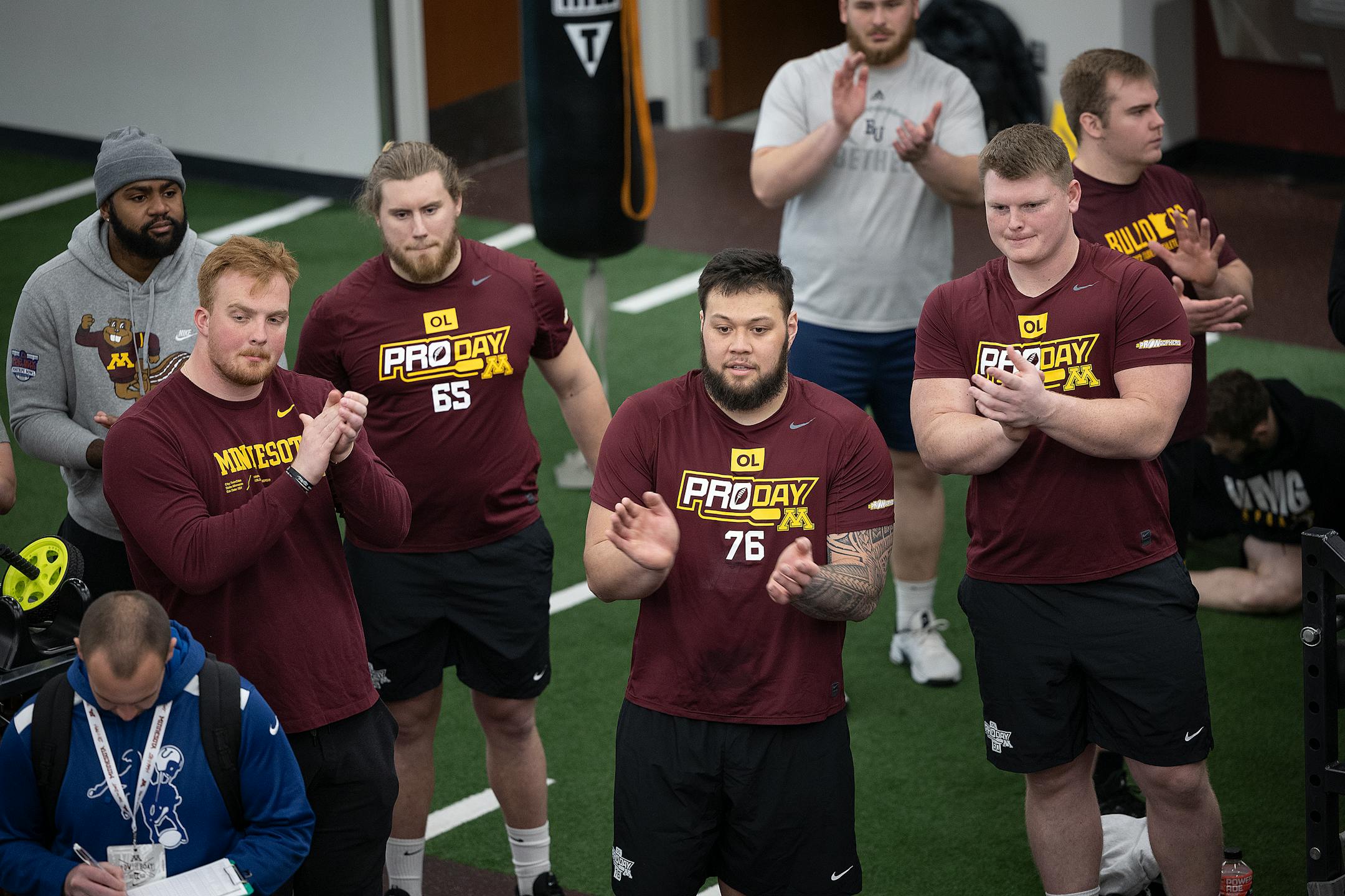 Minnesota football players cheer on as other players bench press 225 pounds during the Minnesota Pro Day.