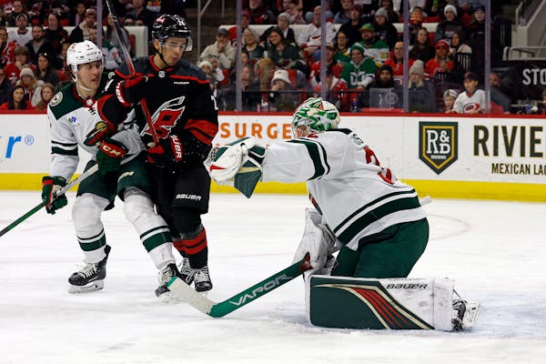 Wild goalie Filip Gustavsson snared the puck in front of the Hurricanes' Seth Jarvis (24) and teammate Brock Faber (7) during the second period Sunday
