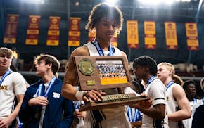 Isaiah Johnson-Arigu takes a moment with the Class 3A championship trophy after he led Totino-Grace to the title with 25 points Saturday against Manka