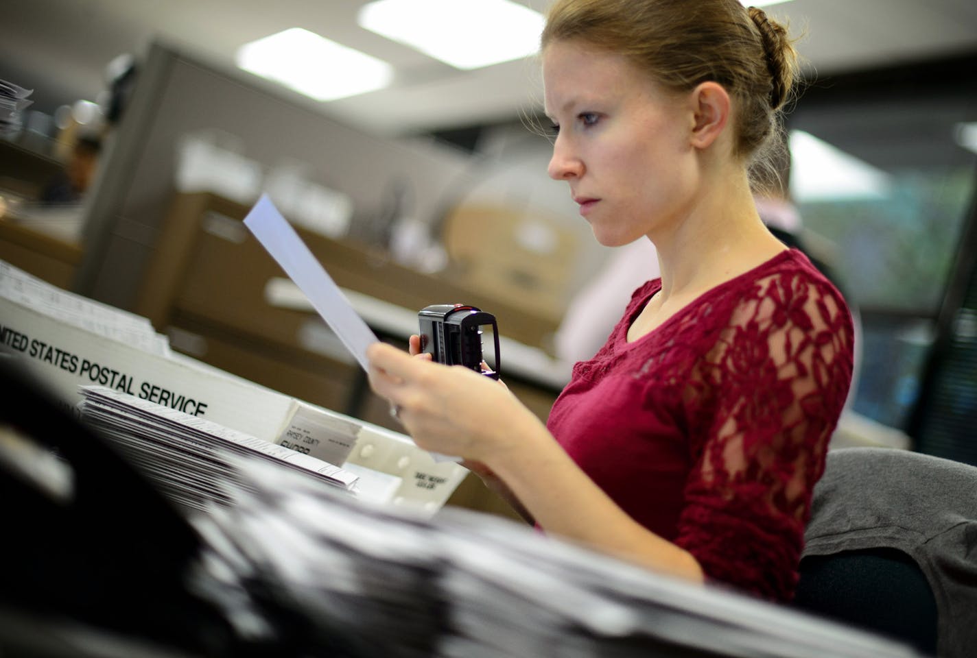 Elections assistant Katherine Estall checked ballots that arrived in the mail over the weekend. ] GLEN STUBBE * gstubbe@startribune.com Processing absentee ballots at the Ramsey County elections office Monday October 20, 2014