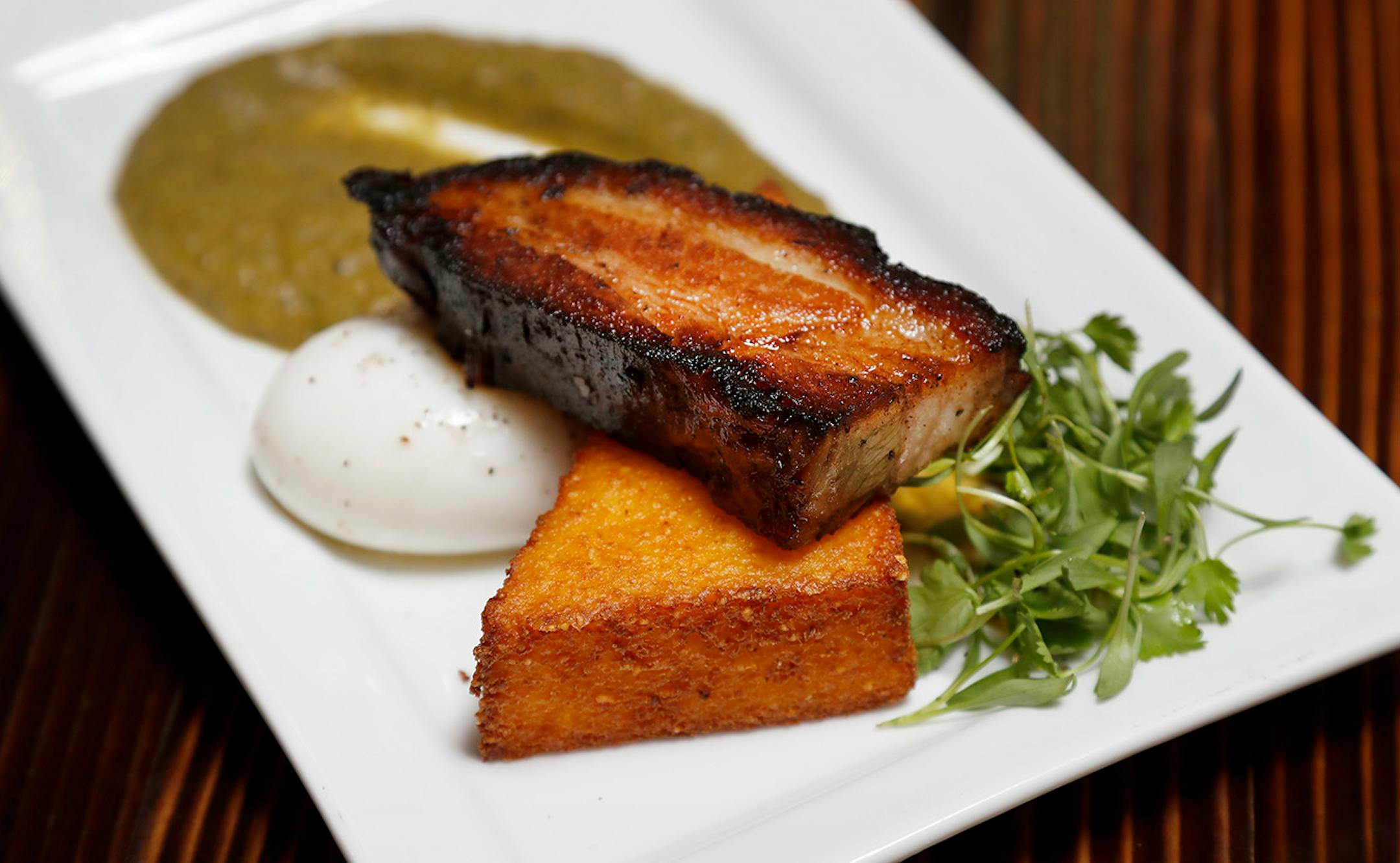 Pork Belly Polenta. Crisped Berkshire pork belly on fried polenta cake served with a soft-cooked egg & green chile at the Northern Waters in Duluth.