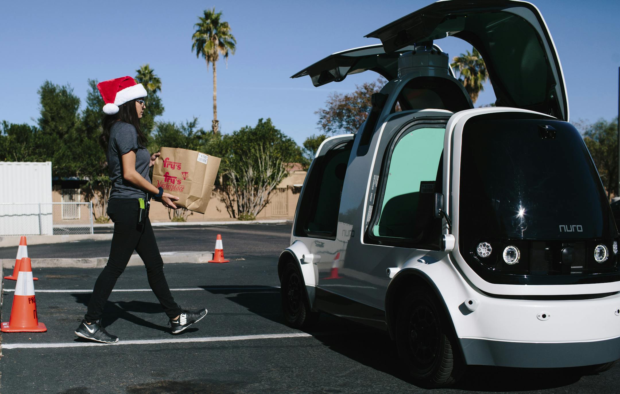 A worker loads an order into a Nuro mini car, which is a self-driving vehicle, outside Fry’s Food Store in Scottsdale, Ariz., Dec. 13, 2018. Nuro’s mini cars are running as part of a partnership with Fry’s Food Store on an autonomous delivery service. (Caitlin O'Hara/The New York Times)