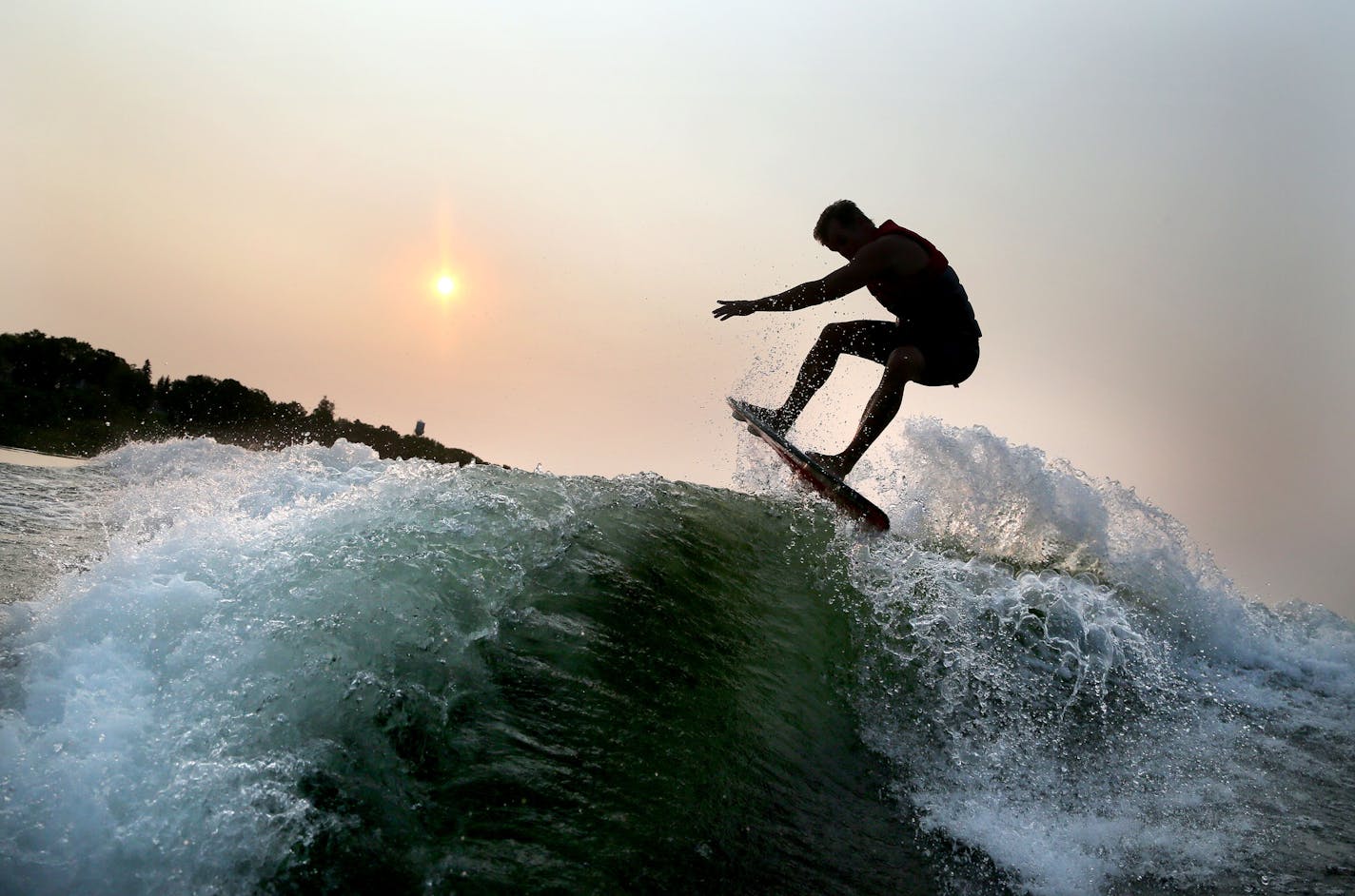 Pro wakeboard surfer Chris Banks practices wakeboard surfing on Lake Minnetonka near dawn.