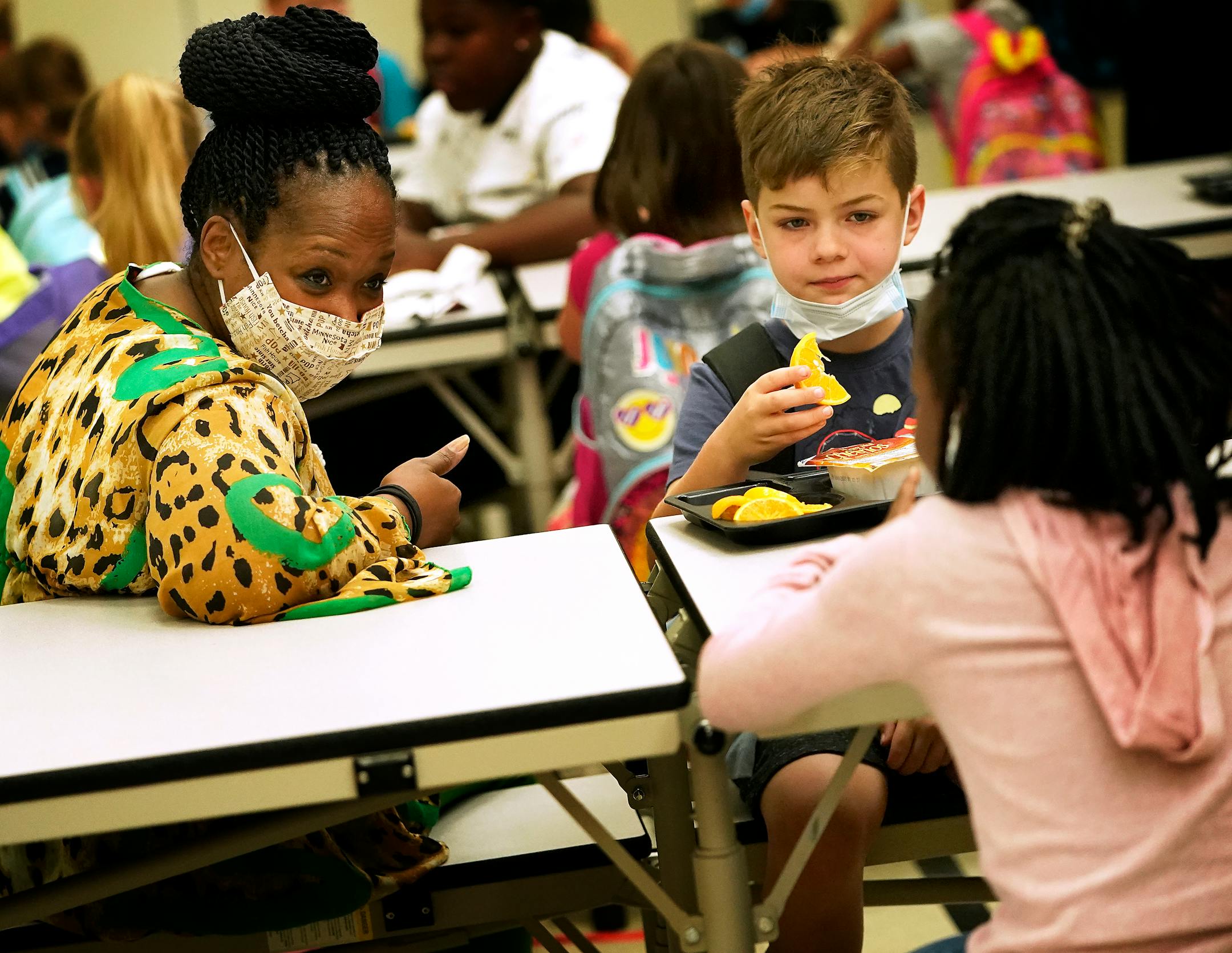 New Hoover Elementary School principal Keisha Davis chatted with first graders Malaika Naimodu, right to left, and Zayne Carlson as they ate breakfast before the start of the first day of school Tuesday in Coon Rapids.   ]