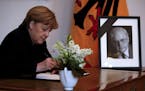 German Chancellor Angela Merkel writes in a condolence book for late former president Roman Herzog, in Berlin, Germany, Wednesday, Jan. 11, 2017. Roma