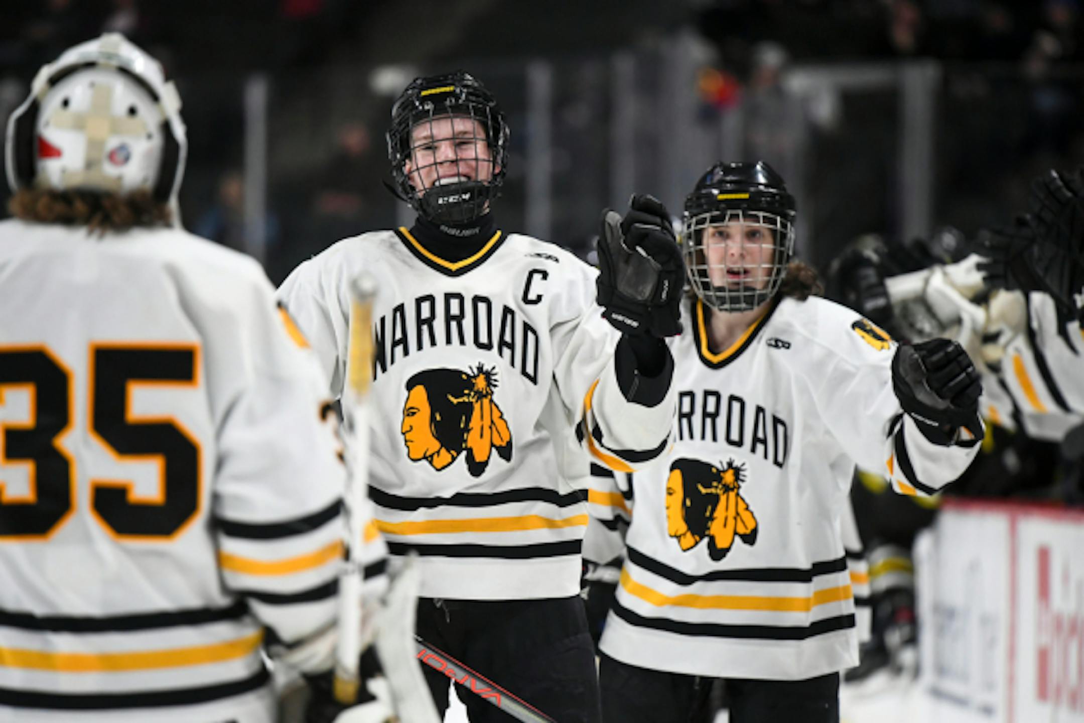 Warroad forward Grant Slukynsky (27), center, celebrated with goaltender Zach Foster (35) after Slukynsky completed a hat trick in the first period against Hutchinson.