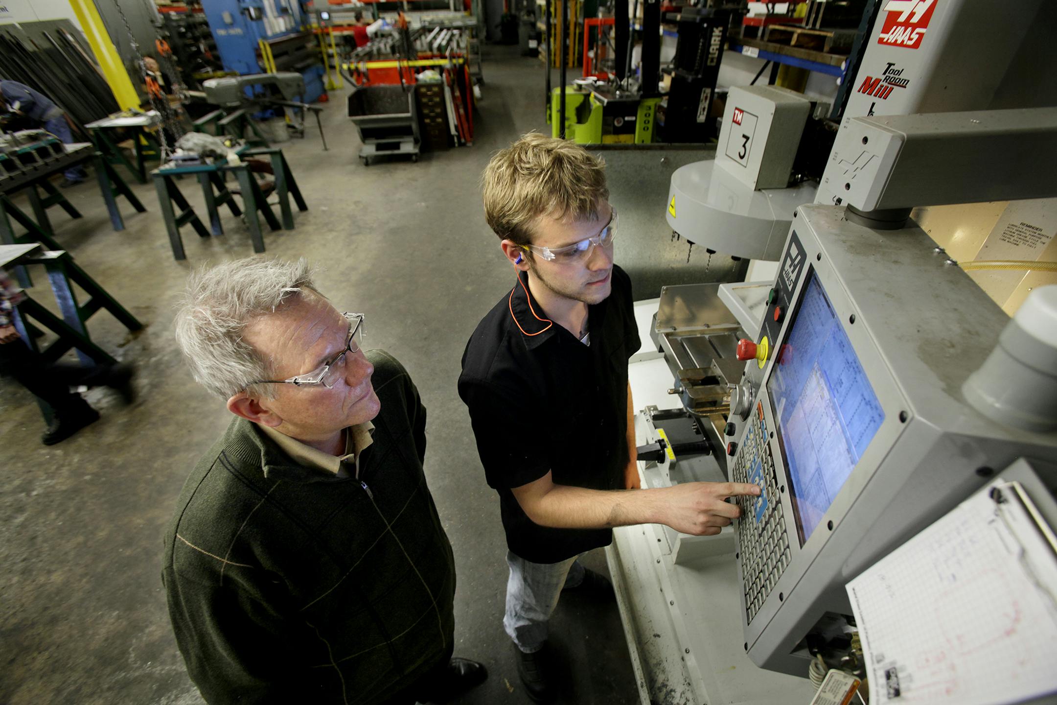 Dunwoody intern, Joe Brudzinski, (right), talks to Erick Ajax, co-owner of E.J. Ajax & Sons Inc., about a part that he was working on at the Fridley, MN plant on March 25, 2013. ] JOELKOYAMA‚Ä¢joel koyama@startribune.com Ajax at EJ Ajax & Sons in Fridley is hosting a Dunwoody College of Technology Da. They are celebraing the graduation of several employee/ apprentices into full journeyman status. This company is a metal stamper that trains folksin high tech manufacturing. It par