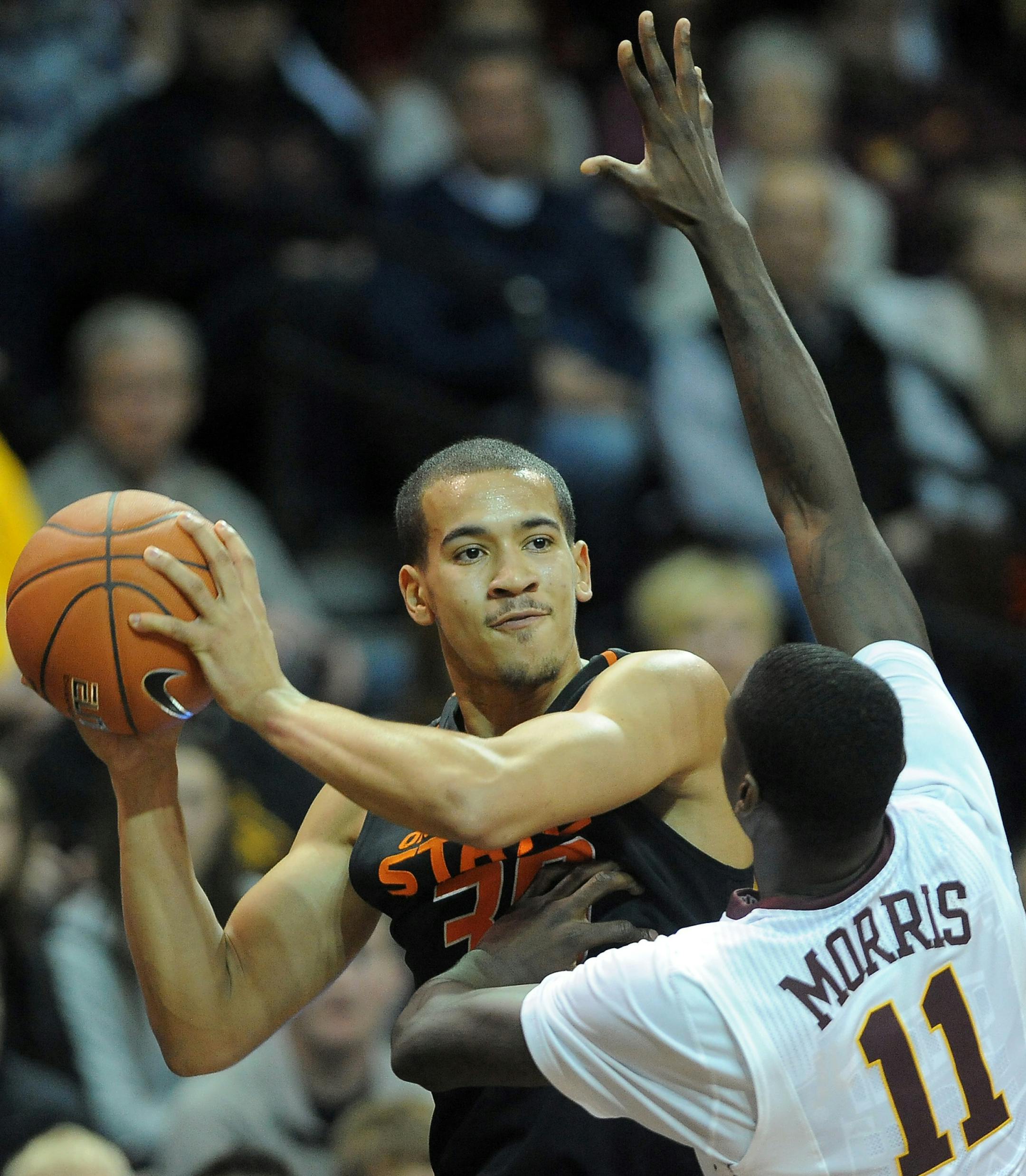 Oklahoma State's Jeffrey Carroll looks to pass around Minnesota's Carlos Morris guards during their game at the Sanford Pentagon in Sioux Falls, S.D. on Saturday, Dec. 12, 2015. (Jay Pickthorn/The Argus Leader via AP) (AP Photo / Argus Leader, Jay Pickthorn)