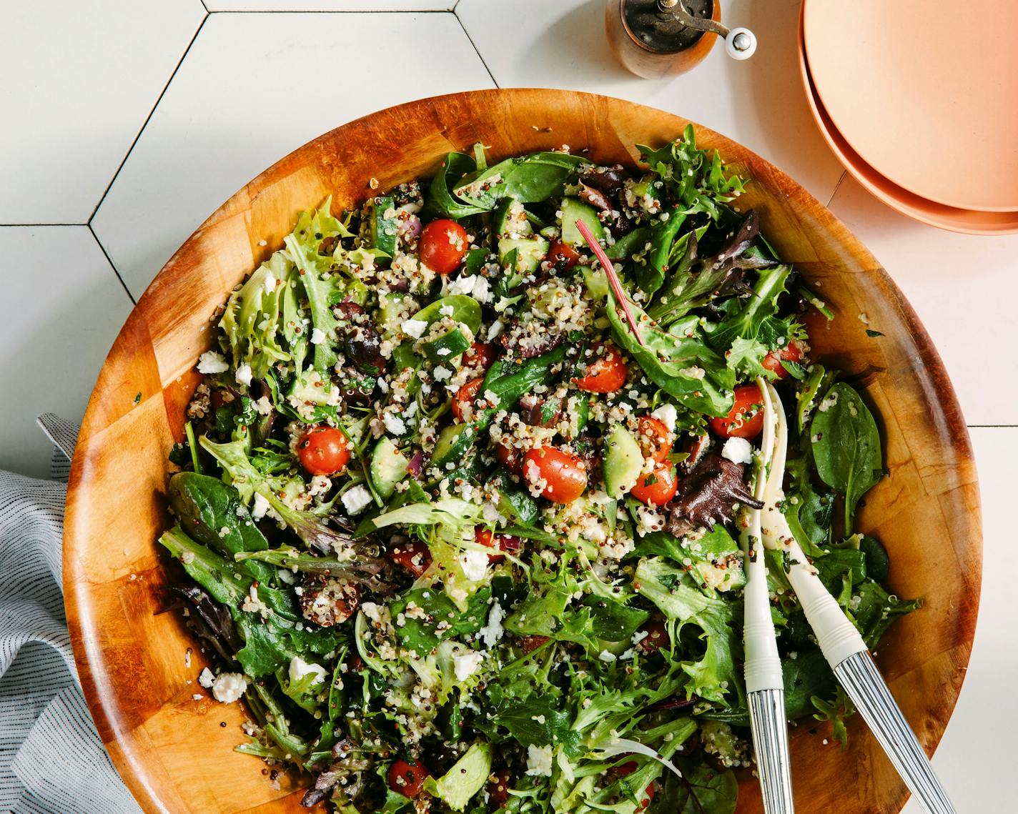 Vibrant Greek Quinoa Salad with tomatoes, lettuce, and various veggies in a bowl. From the cookbook "Big Bites" by Kat Ashmore.