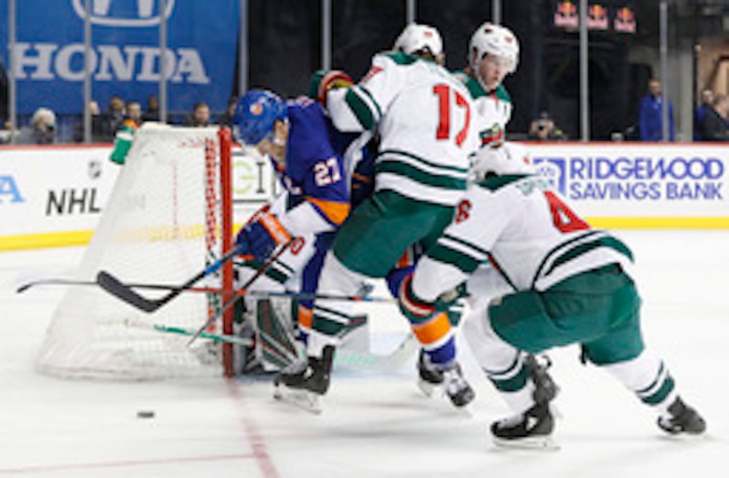 Minnesota Wild left wing Marcus Foligno (17) and Minnesota Wild defenseman Jared Spurgeon (46) defend as they and teammates sandwich New York Islanders left wing Anders Lee (27) near the net in the second period of an NHL hockey game, Sunday, Feb. 10, 2019, in New York. (AP Photo/Kathy Willens)